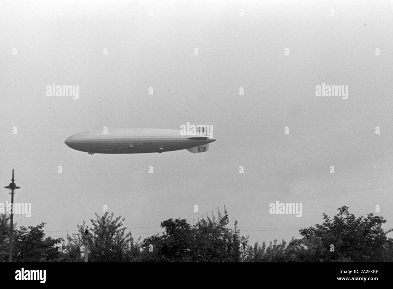 Zeppelin LZ 129 Hindenburg bei der über dem Olympiafahrt Reichssportfeld à Berlin, Deutschland 1930er Jahre. Zeppeilin LZ 129 Hindenburg à son tour olympique Reichssportfeld sur terrain de sport à Berlin, Allemagne, 1930. Banque D'Images