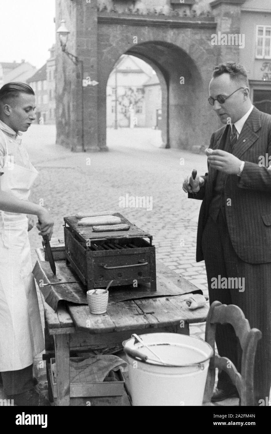 Un Würstchen kauft ein Mann Würstchenstand in Deutschland, 1930er Jahre. Homme achat une saucisse à un open air grill, Allemagne 1930. Banque D'Images