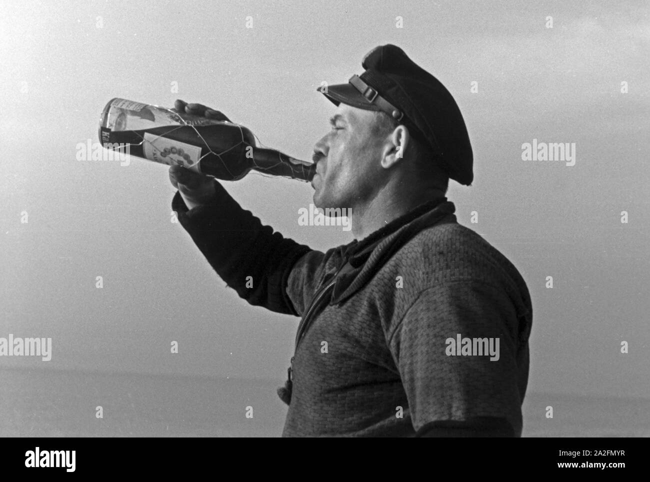 Hochseefischer nimmt ein einen Schluck Rum aus der Flasche, Deutschland 1930 er Jahre. Un pêcheur en haute mer en prenant un coup de rhum, Allemagne 1930. Banque D'Images