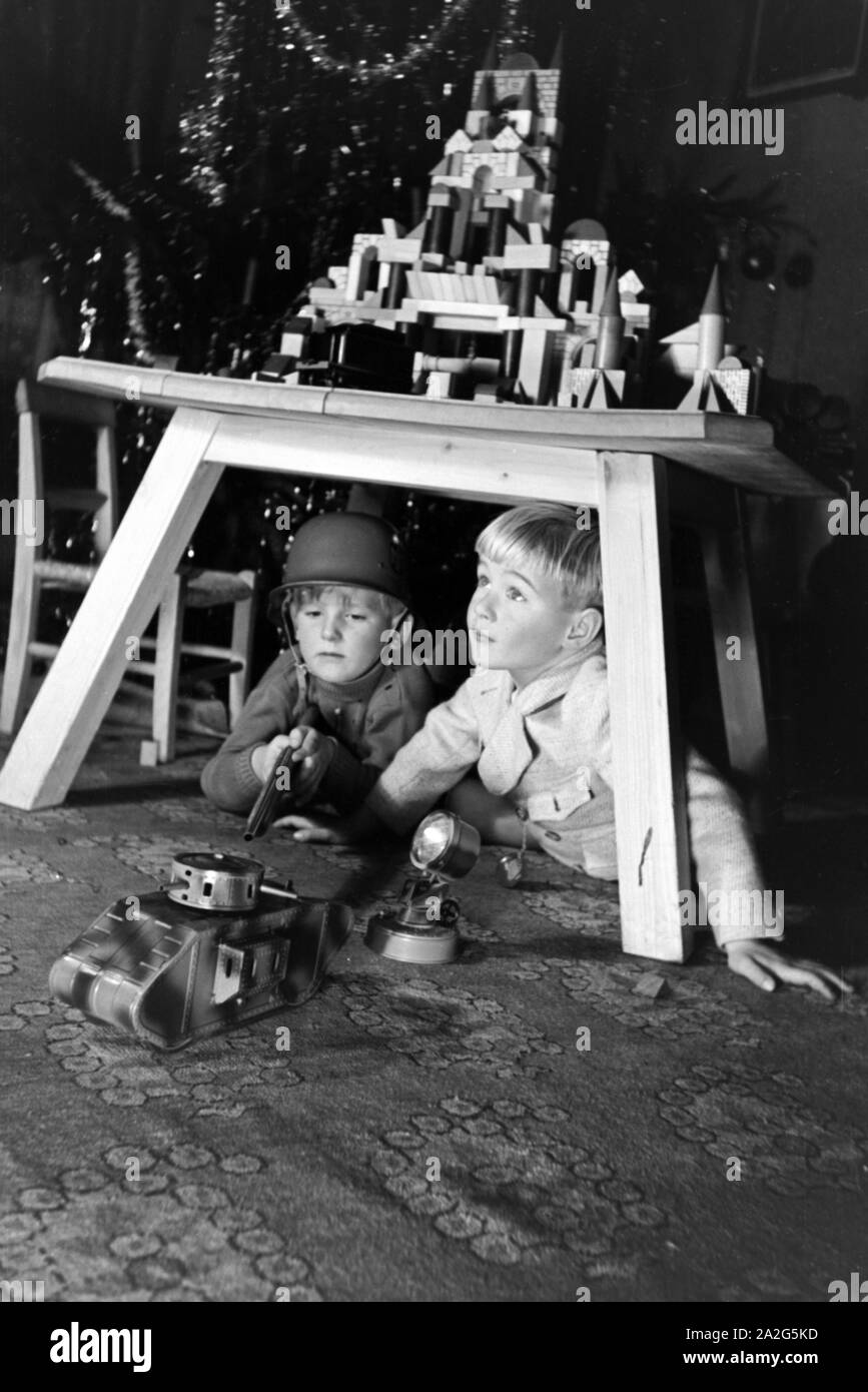 Zwei Jungen spielen am Weihnachtsabend mit Stahlhelm Gewehr und Soldaten Deutschland, 1938. Deux garçons soldats jouant avec un casque d'acier et un fusil jouet sous l'arbre de Noël, de l'Allemagne 1930 Banque D'Images