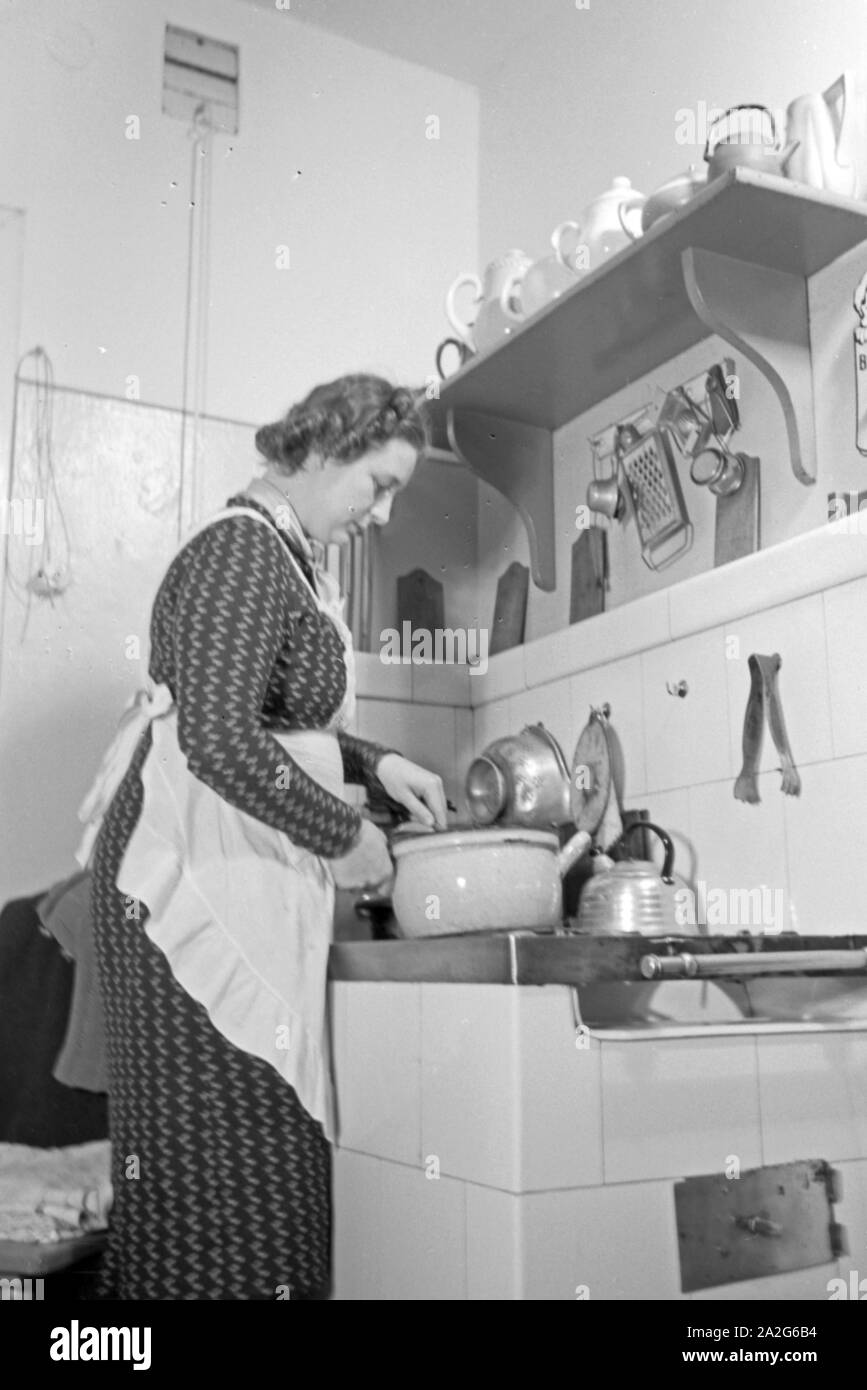 Eine Frau steht am herd in der Küche und kocht, Deutschland 1930 er Jahre. Une femme debout dans la cuisine sur la cuisson au four, l'Allemagne des années 1930. Banque D'Images