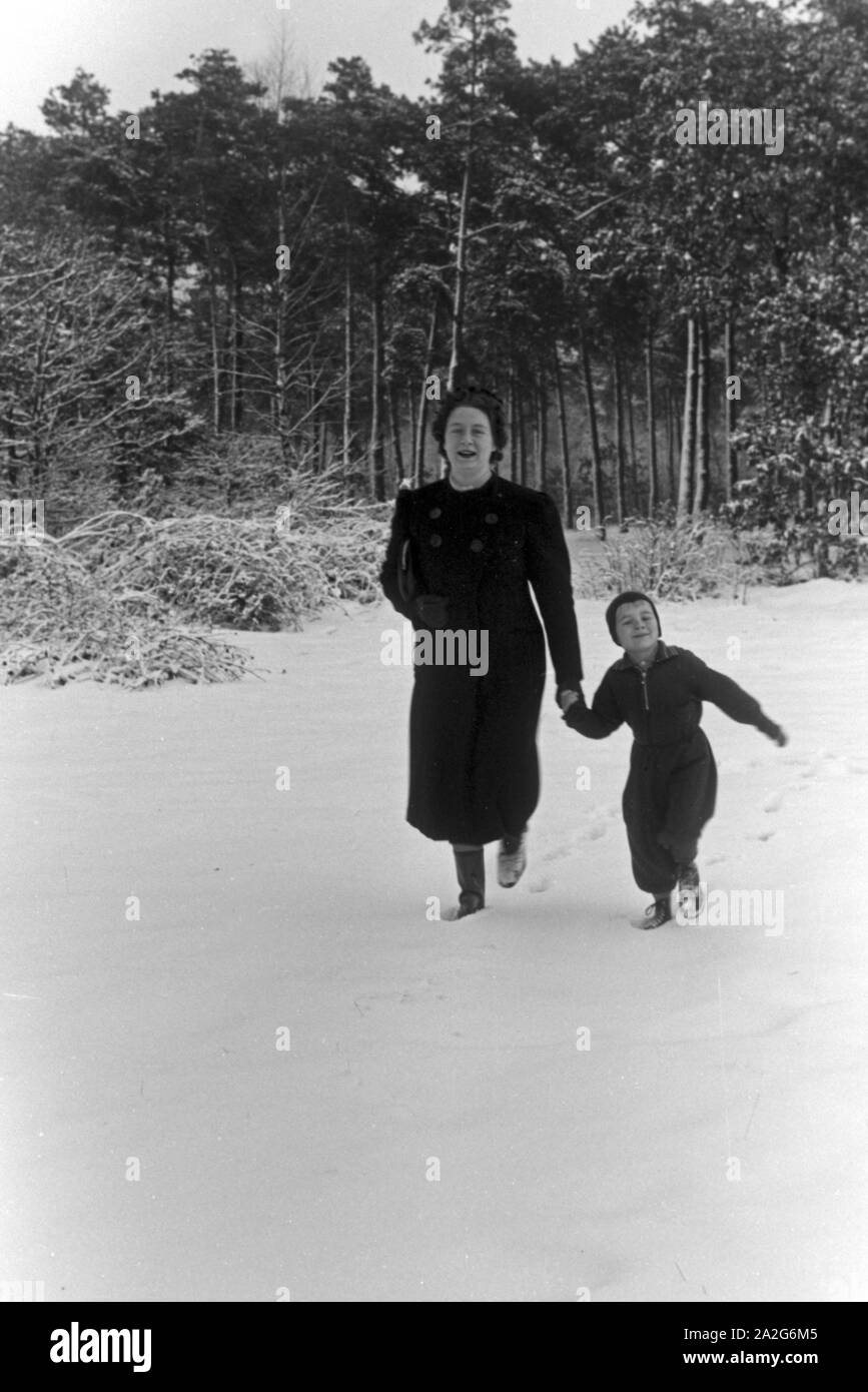 Ein kleiner Junge an der Hand-senneur Mutter im Schnee, Deutschland 1930er Jahre. Un petit garçon sur la main de sa mère dans la neige, l'Allemagne des années 1930. Banque D'Images
