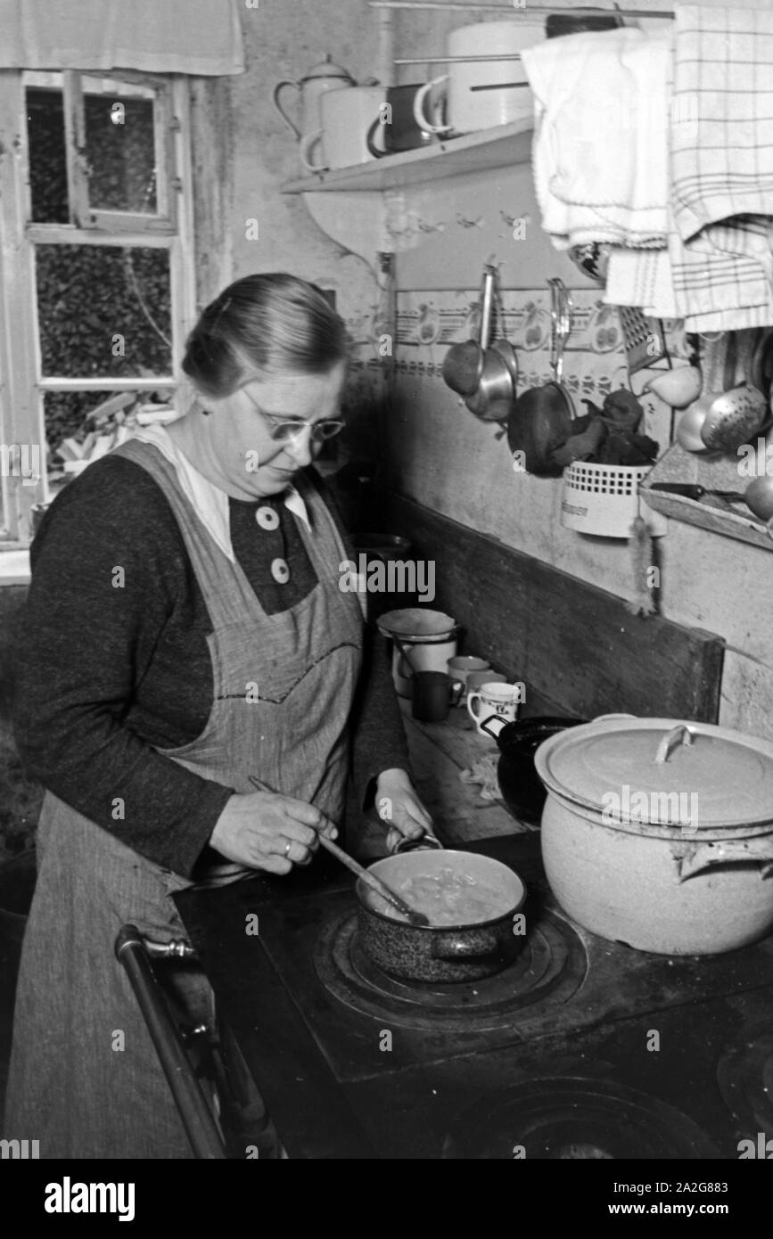Die Großmutter kocht für die Knipser Vierlinge, 1930er Jahre Deutschland. Grand-mère est en train de préparer les repas pour les filles, Knipser quadruplet Allemagne 1930. Banque D'Images