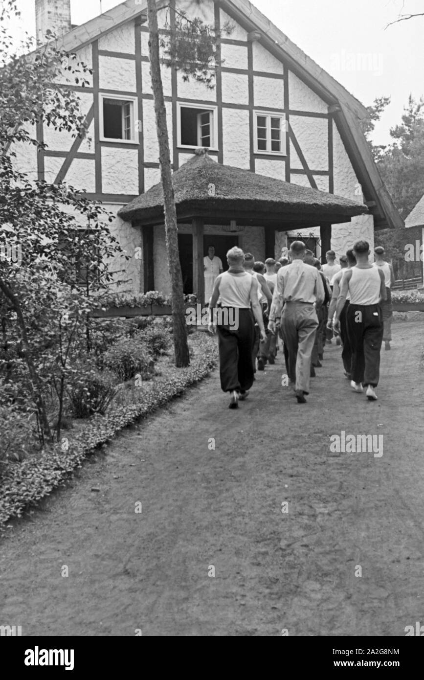 Männer auf dem Weg in das KdF Sportheim Belzig dans der Mark Brandenburg, Deutschland 1930 er Jahre. Les hommes allant à la maison du club sportif à Belzig à Brandebourg, Allemagne 1930. Banque D'Images
