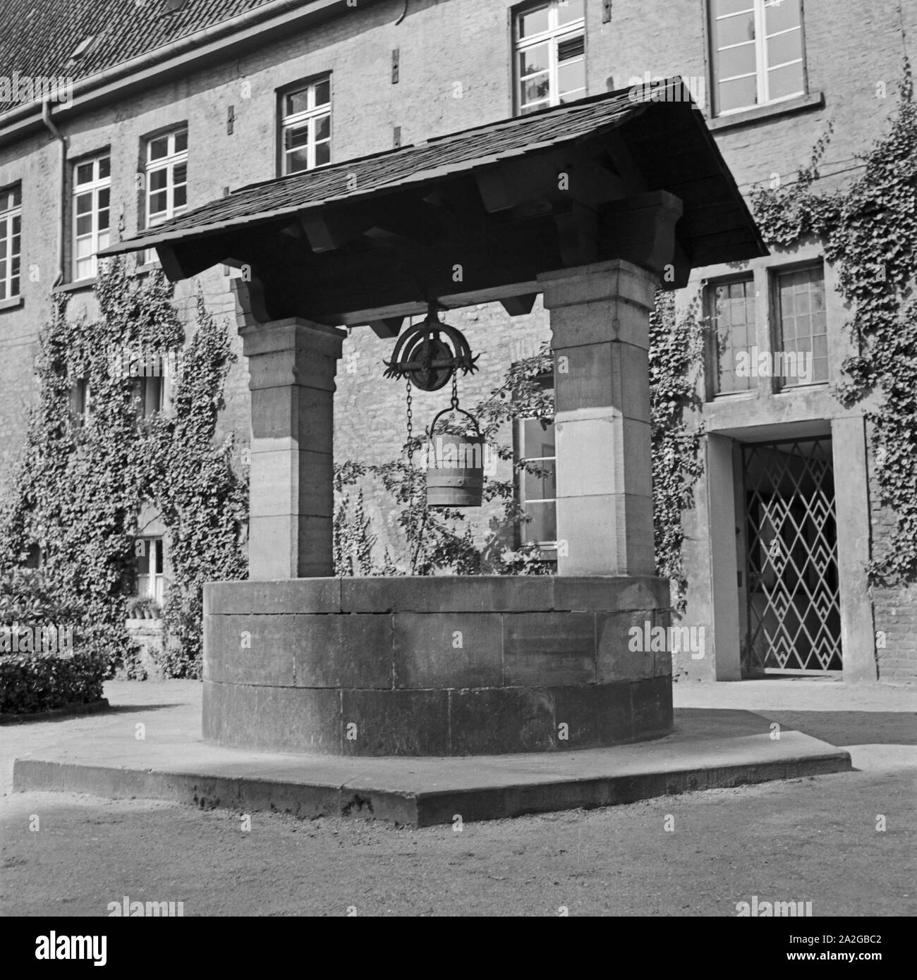 Historischer Ziehbrunnen einem Hof à Gladbach, Deutschland 1930 er Jahre. Bien dessiner historique dans une cour à Gladbach, Allemagne 1930. Banque D'Images