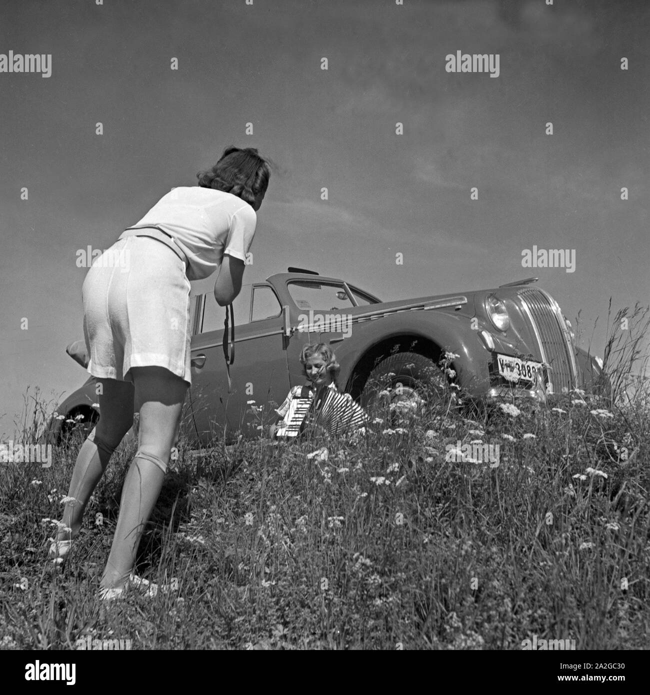 Zwei junge Frauen fotografieren sich vor einem Opel Olympia in Österreich, 1930er Jahre. Deux jeunes femmes prenant des photos d'eux-mêmes en face d'une Opel Olympia à l'Autriche, 1930. Banque D'Images