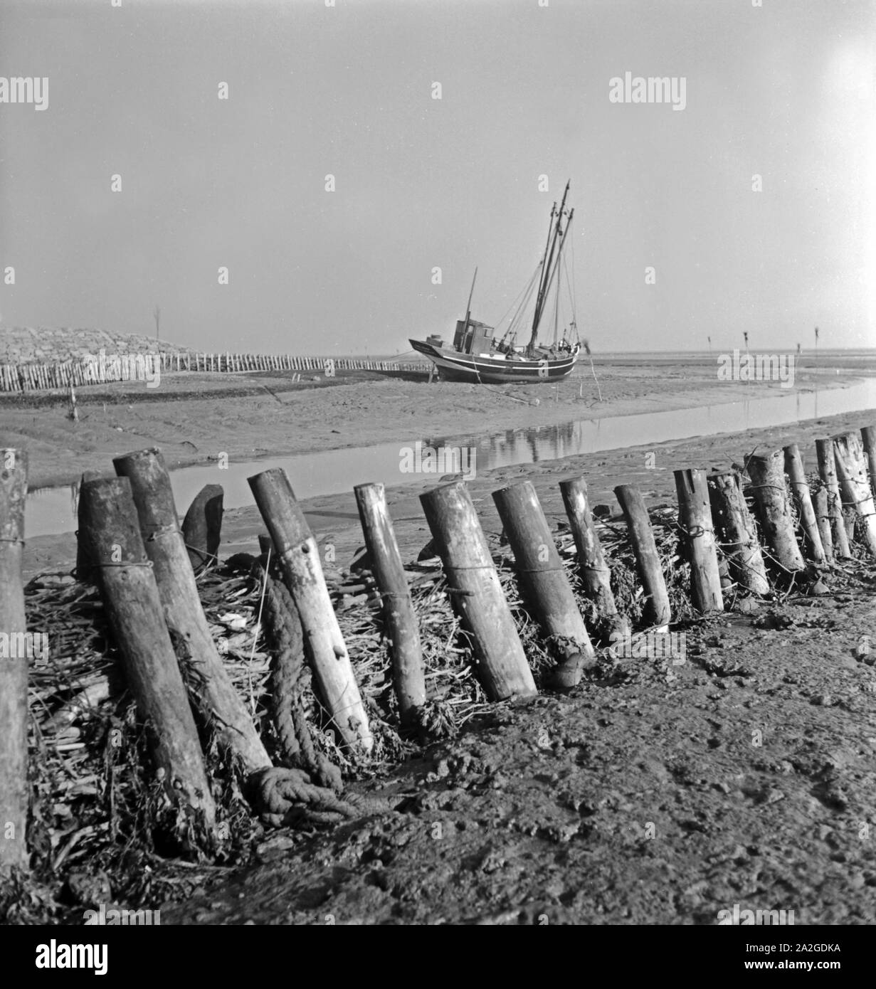 Bei Ebbe liegt ein Fischkutter une terre en Ostfriesland, Deutschland 1930er Jahre. Un chalutier de poissons sur le sol à marée basse en Frise orientale, en Allemagne 1930. Banque D'Images