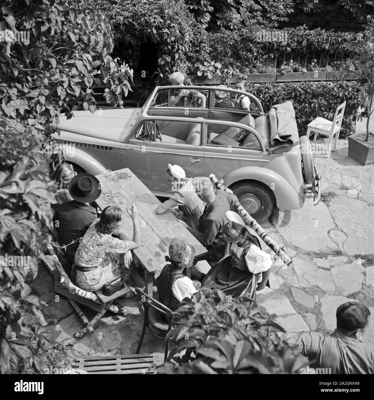 Mit dem Opel zu einem Ausflug à ein Gartenrestaurant, Deutschland 1930er Jahre. Avec une Opel convertible en un restaurant avec jardin, Allemagne 1930. Banque D'Images