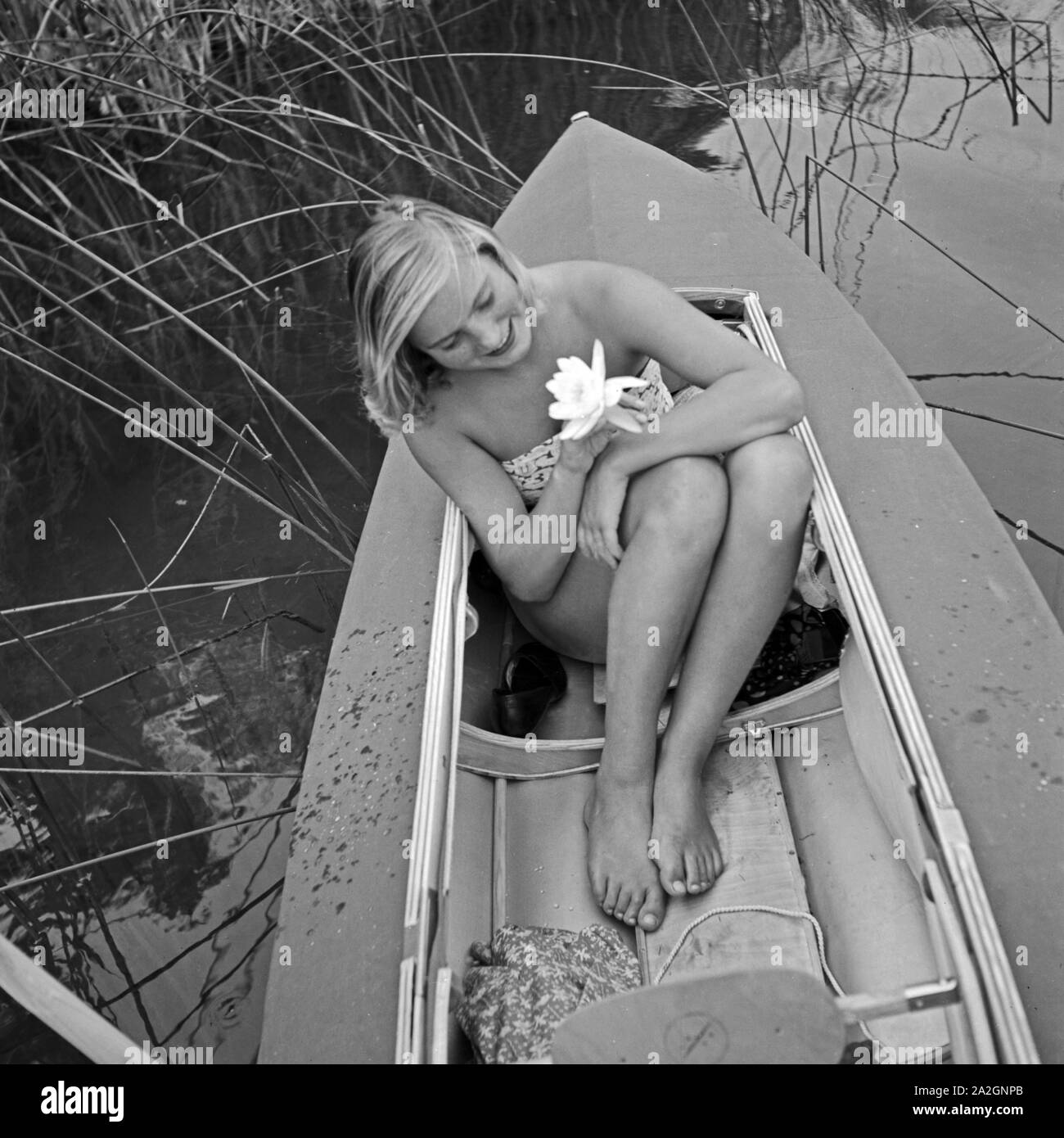 Eine junge Frau mit einer Seerose in Ihrem Klepper Faltboot, Deutschland 1930 er Jahre. Une jeune femme avec un nénuphar dans un bateau pliable Klepper, Allemagne 1930. Banque D'Images