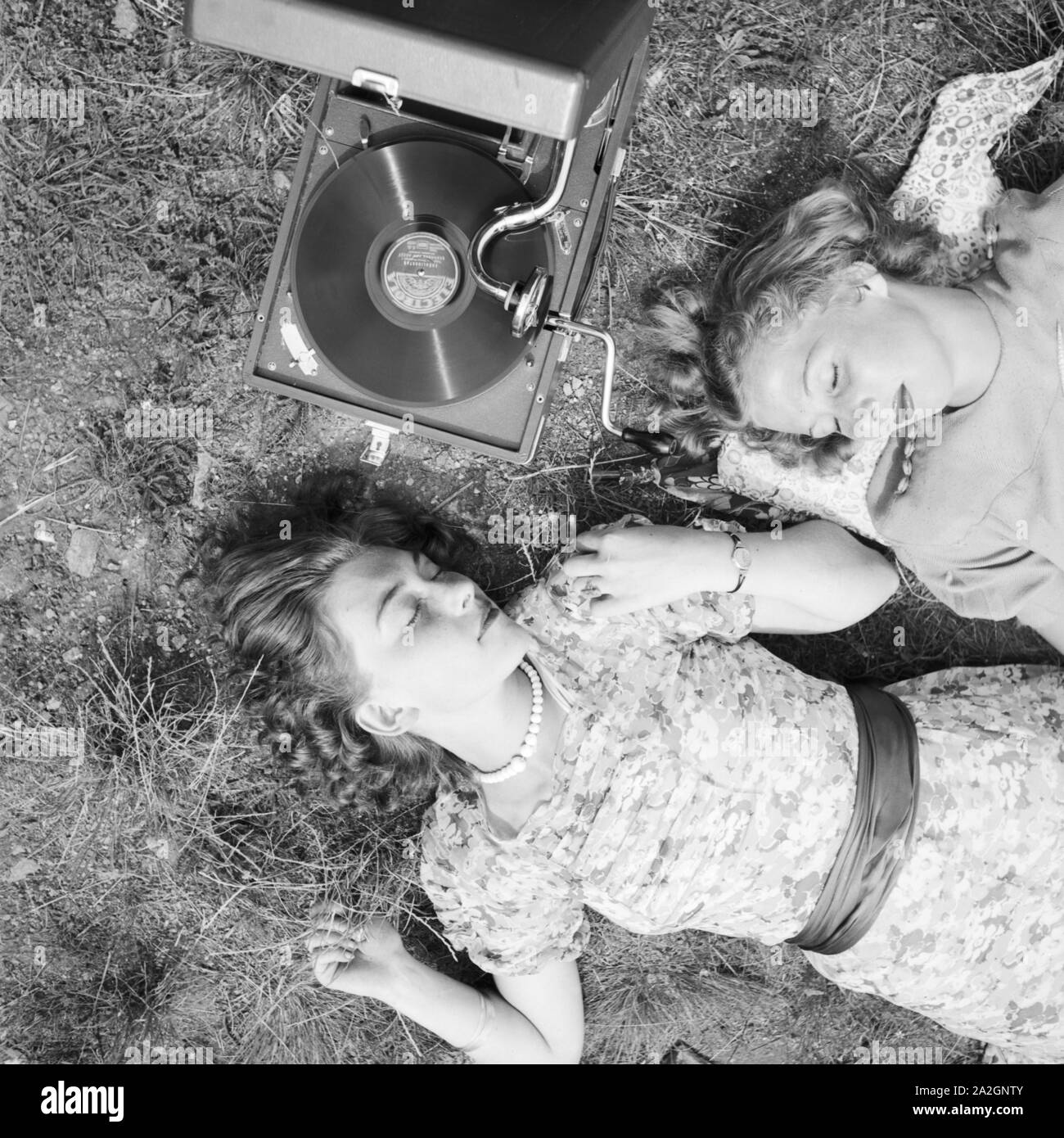 Zwei junge Frauen und liegen im Gras hören die neuesten Schlager vom Electrola, Koffergrammophon Deutschland 1930 er Jahre. Deux jeunes femmes se trouvant dans une pelouse et d'écouter les derniers hits de leur gramophone Electrola, Allemagne 1930. Banque D'Images