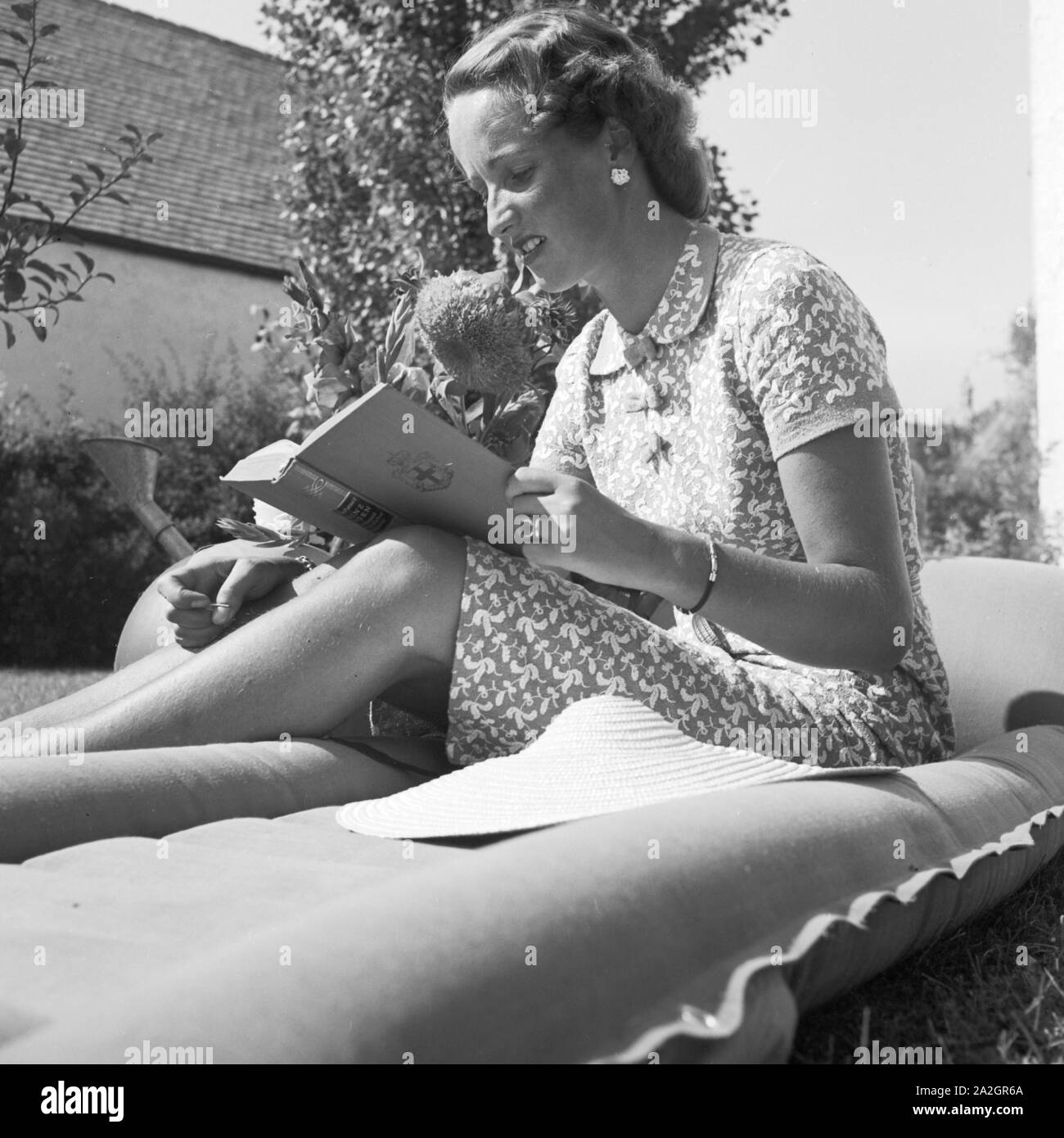 Eine junge Frau liegt auf einer Wiese und einem Buch liest, Deutschland 1930 er Jahre. Une jeune femme sur une pelouse, lire un livre, de l'Allemagne des années 1930. Banque D'Images