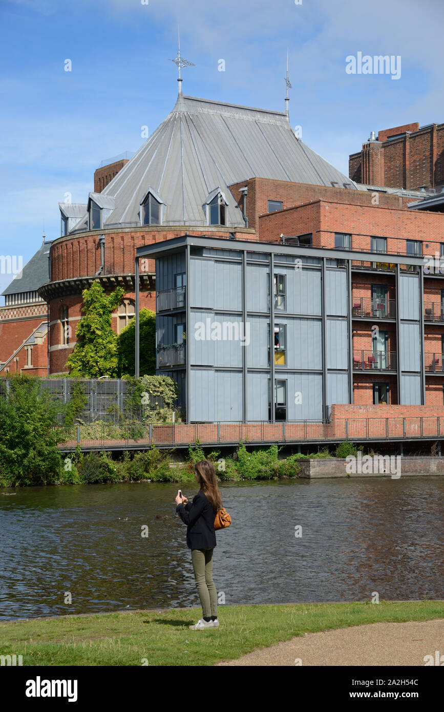 Jeune femme de prendre des photos sur les berges de la Rivière Avon en face du Royal Shakespeare Theatre ou théâtre Stratford-upon-Avon en Angleterre Banque D'Images
