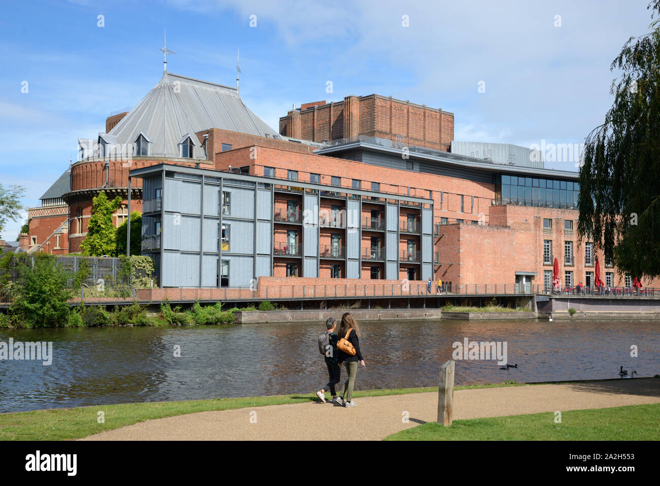 Deux femmes touristes à pied le long de la Rivière Avon en face du Royal Shakespeare Theatre sur les rives de la rivière Avon Stratford-upon-Avon Banque D'Images