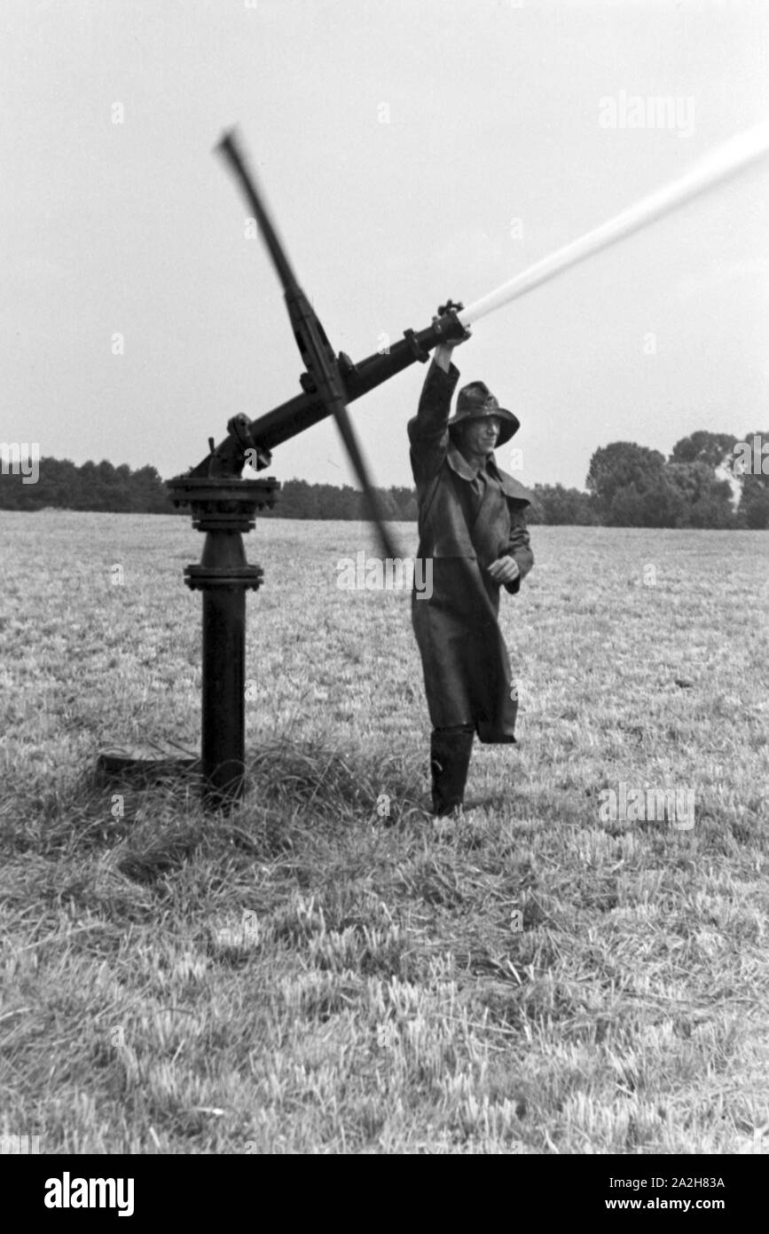 Eine im Regenanlage Kartoffelacker landwirtschaftlichen Einsatz bei einem 1930er Jahre, Deutschland. Un système de gicleurs dans son usage agricole à un champ de pommes de terre, de l'Allemagne des années 1930. Banque D'Images