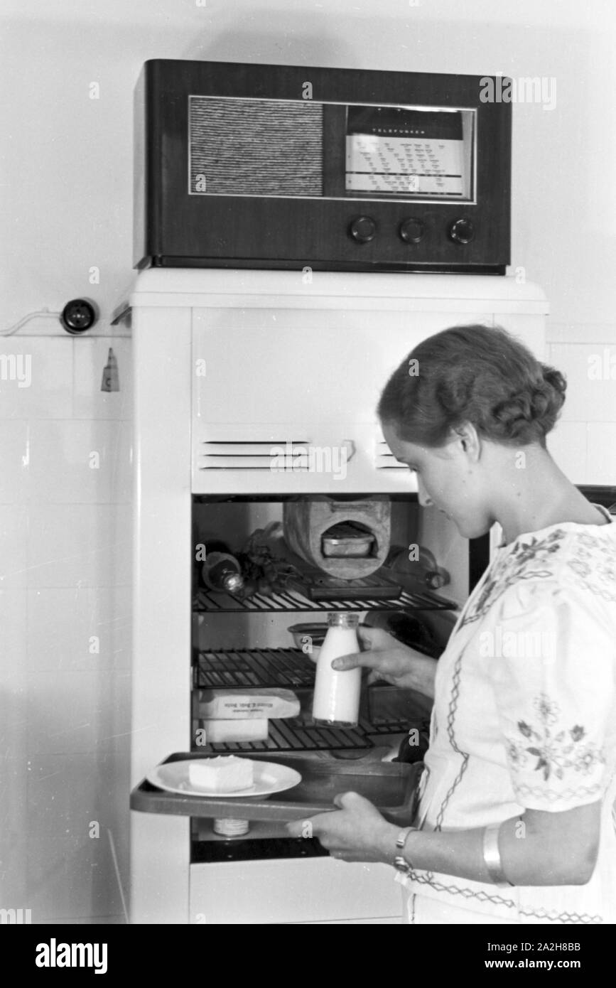 Eine Frau am Kühlschrank, auf dem das Radio steht, Deutschland 1930 er Jahre. Une femme par le réfrigérateur, où la radio est à l'Allemagne, 1930. Banque D'Images