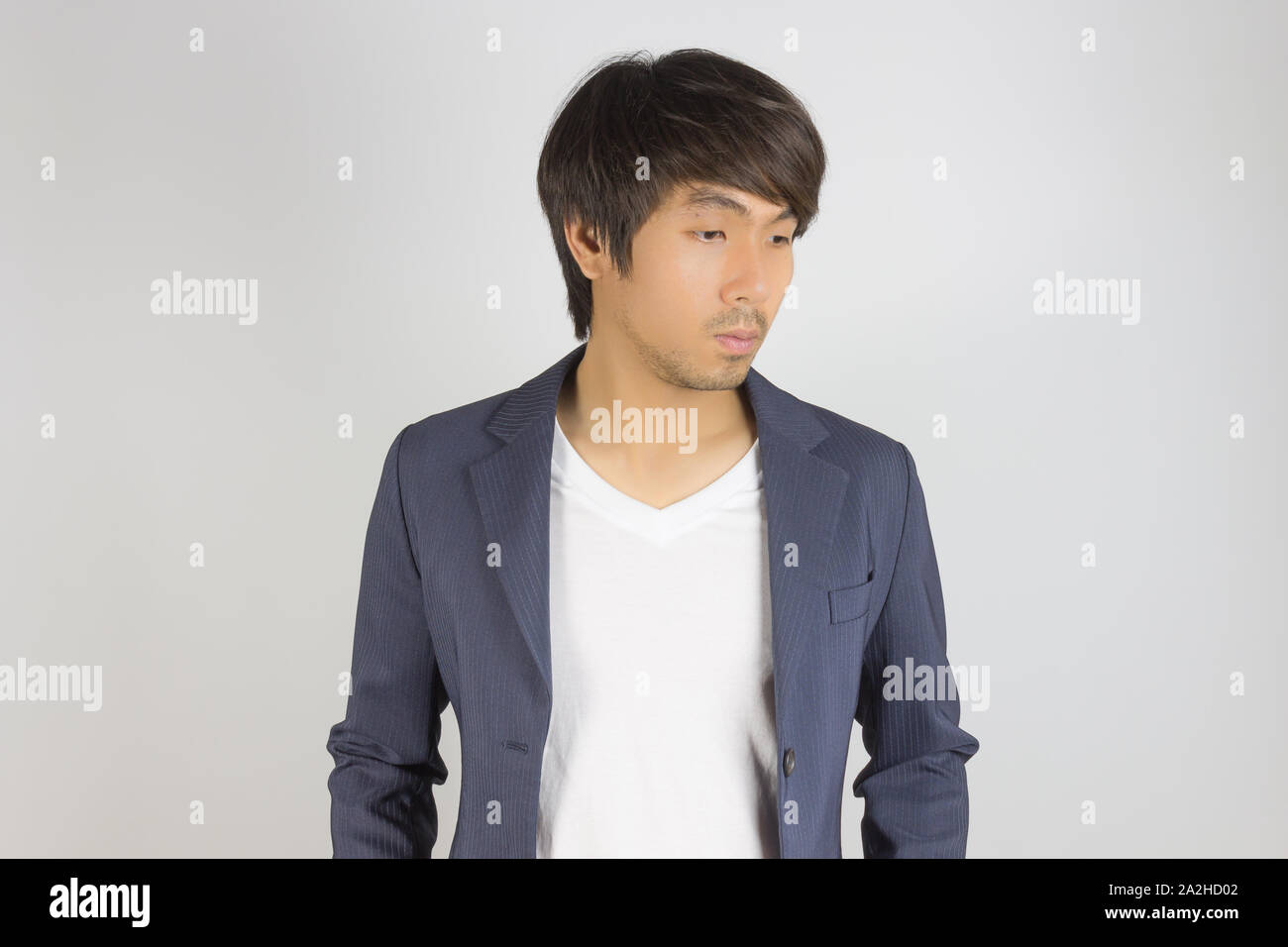 Portrait Asian Businessman en costume bleu marine avec T-Shirt regardez ci-dessous sur fond gris. Businessman porter en mode combinaison officielle semi st Banque D'Images