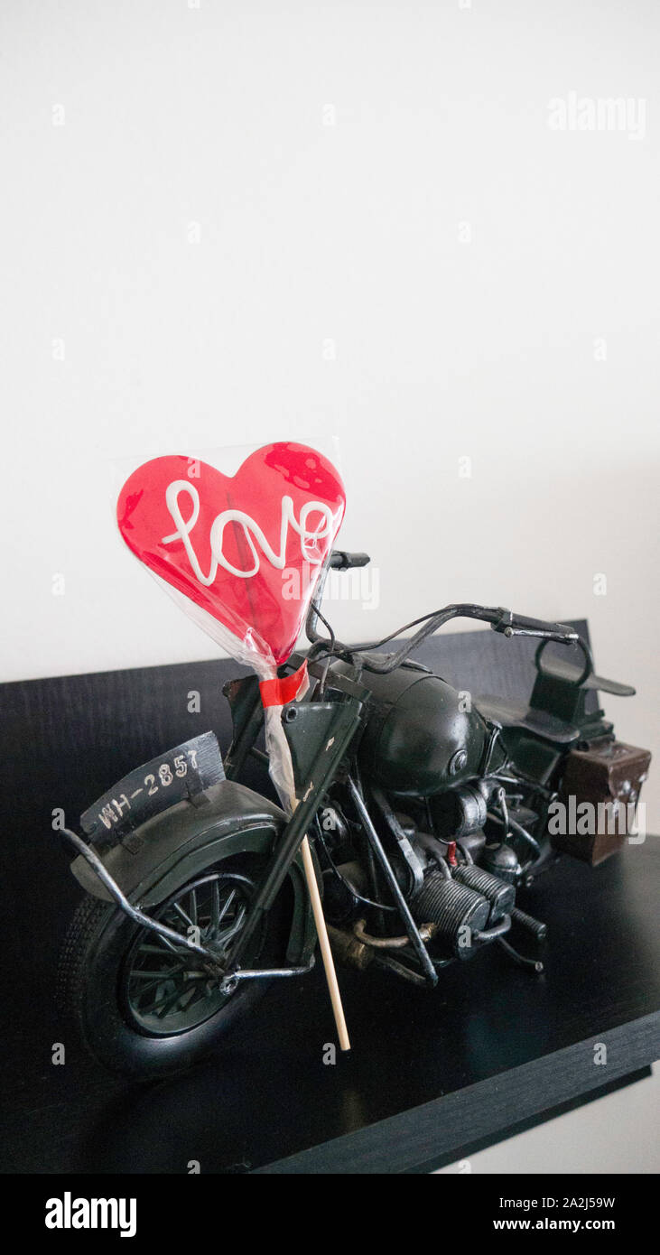 Jouet moto métal modèle sur une planche en bois avec une sucette en forme de cœur Banque D'Images