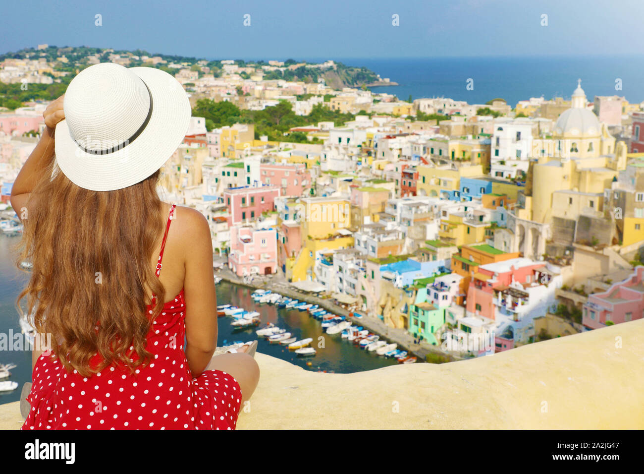 Vacances en Italie. Vue arrière de Beautiful Girl with hat sur le mur à la vue imprenable sur l'île de Procida, Naples, Italie. Banque D'Images
