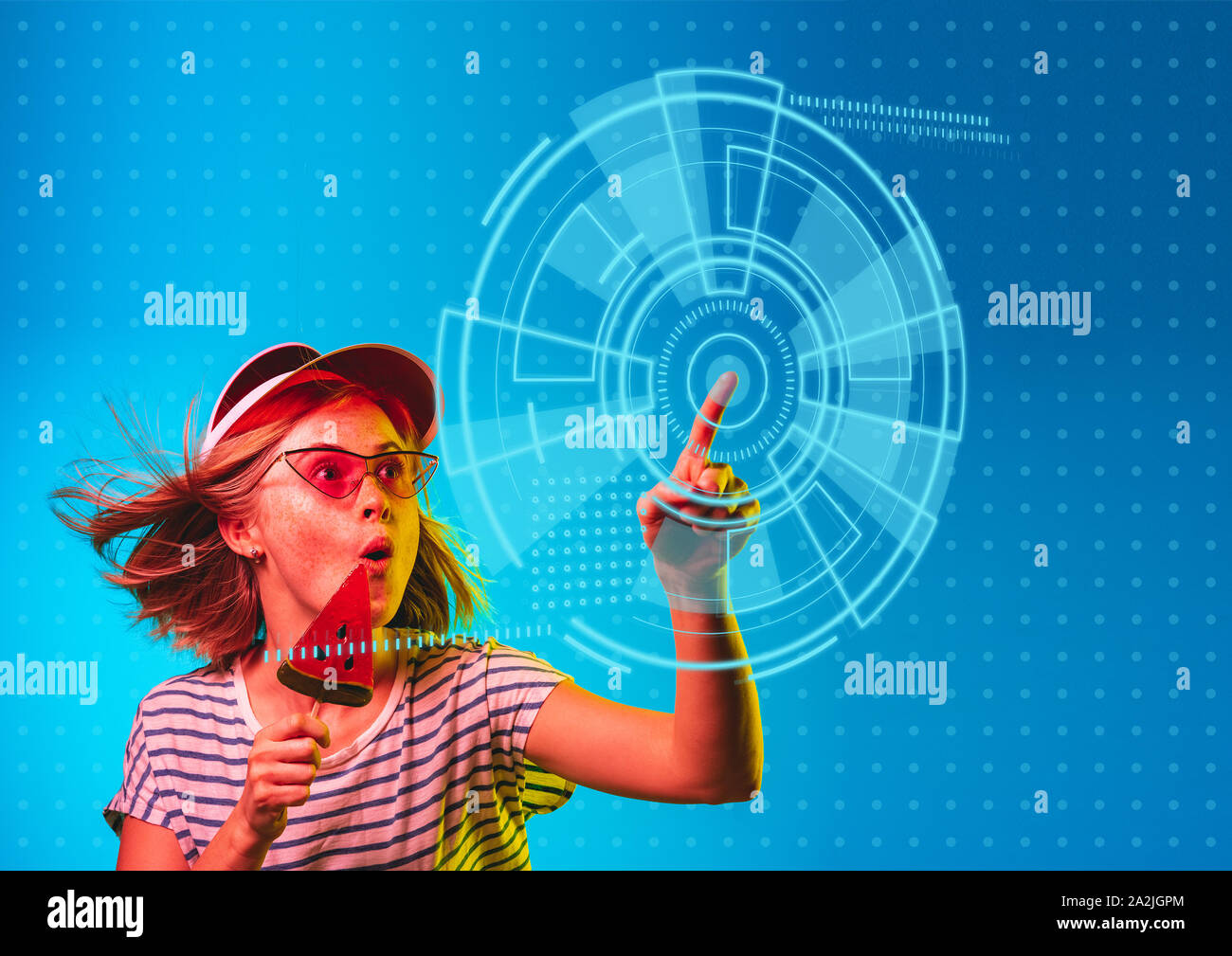 Technologies. Young caucasian woman's de toucher la réalité virtuelle dans la lumière au néon sur fond bleu. Concept d'émotions humaines, l'expression du visage, gadgets et technologies modernes. Copyspace. Banque D'Images