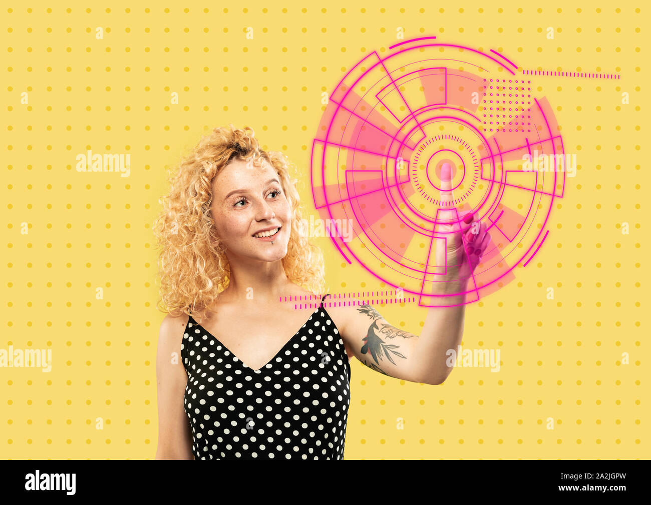 Les technologies modernes. Young caucasian woman's de toucher la réalité virtuelle dans la lumière au néon sur fond jaune. Concept d'émotions humaines, l'expression du visage, gadgets et technologies modernes. Copyspace. Banque D'Images