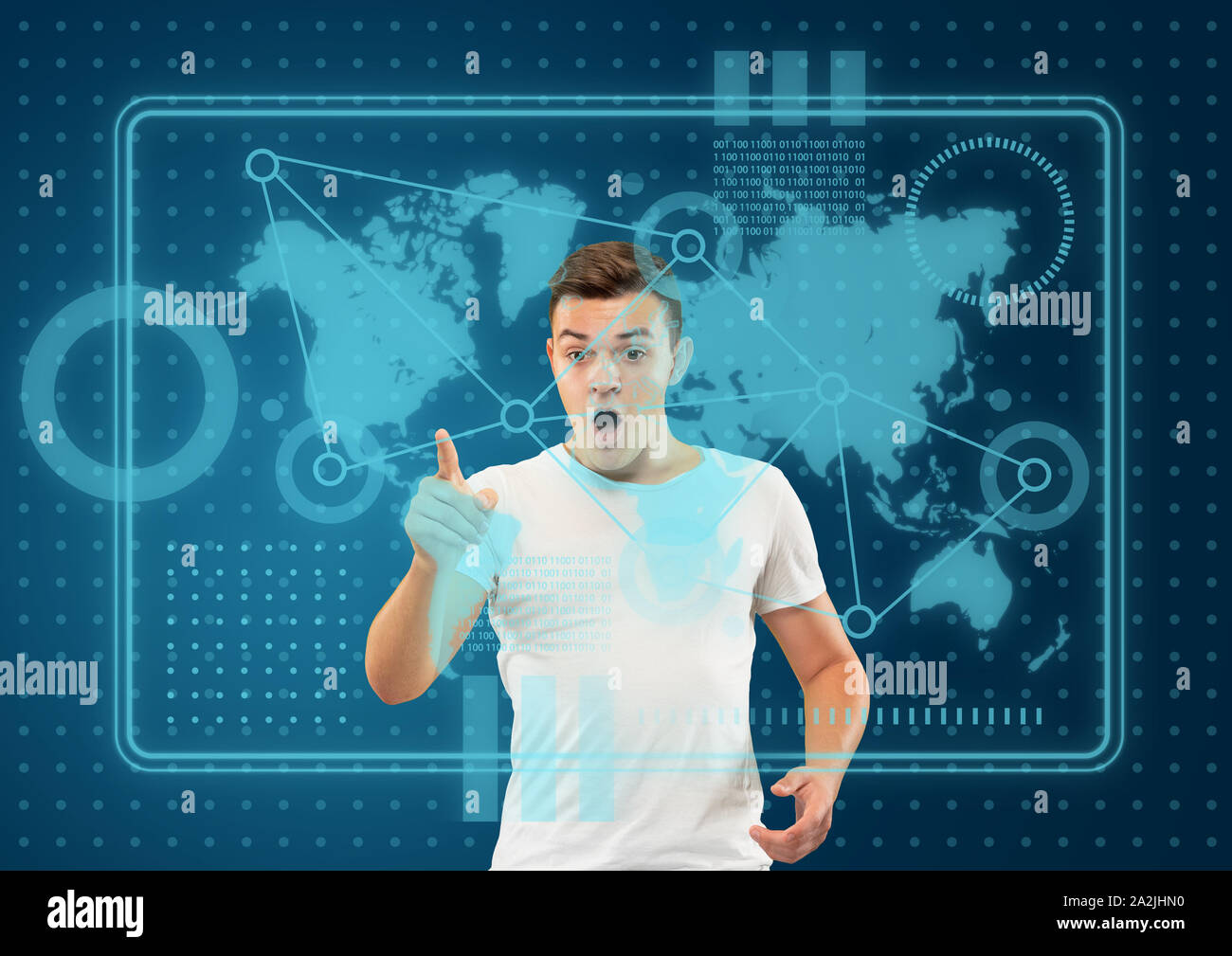 Les technologies modernes. Young caucasian man touche à la réalité virtuelle dans la lumière au néon sur fond bleu. Concept d'émotions humaines, l'expression du visage, gadgets et technologies modernes. Copyspace. Banque D'Images