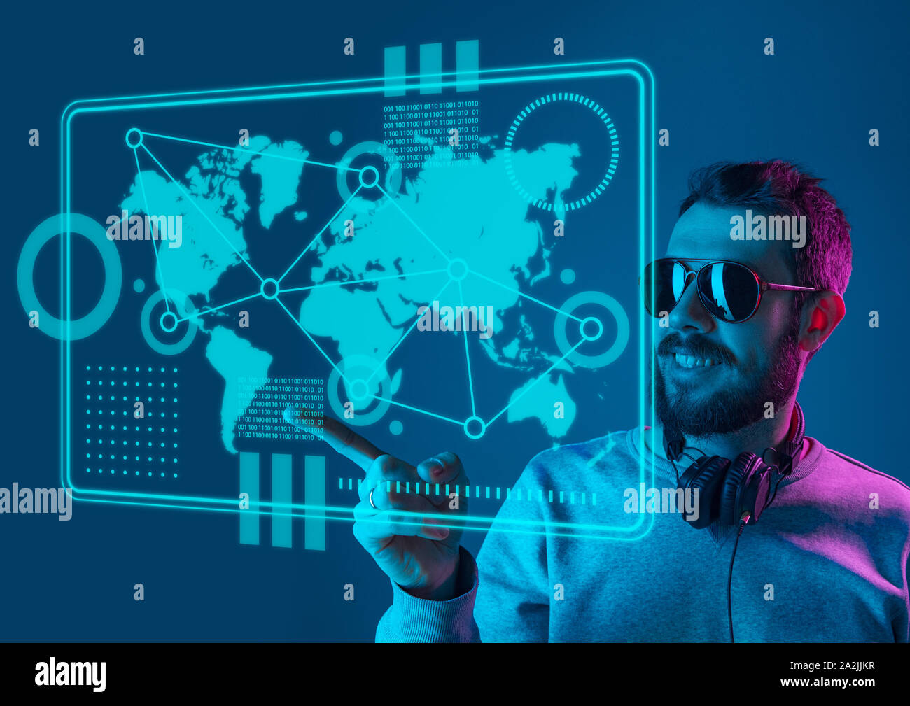 Les technologies modernes. Young caucasian man touche à la réalité virtuelle dans la lumière au néon sur fond bleu. Concept d'émotions humaines, l'expression du visage, gadgets et technologies modernes. Copyspace. Banque D'Images