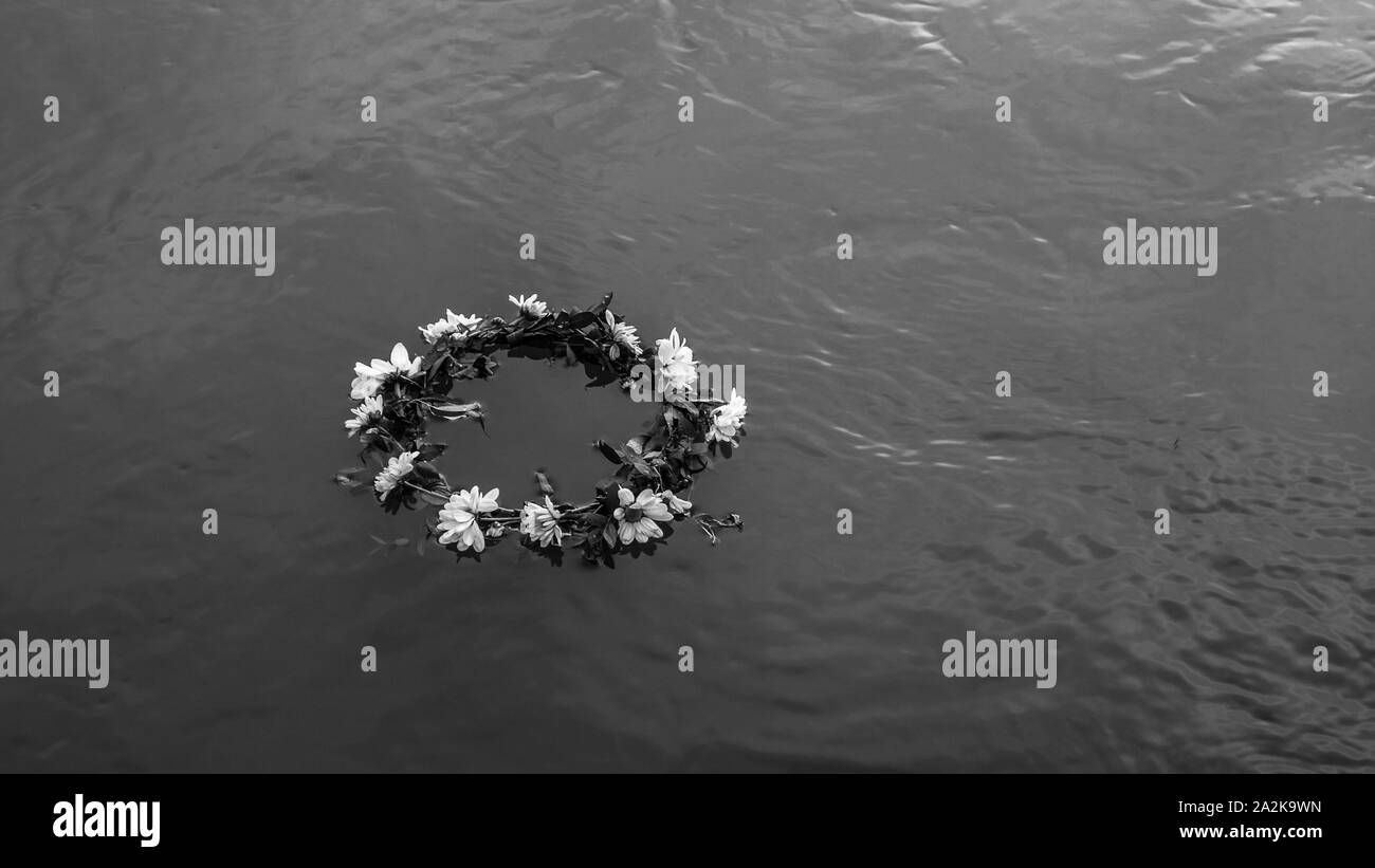 Photo en noir et blanc d'une couronne de fleurs flottant sur l'eau Banque D'Images