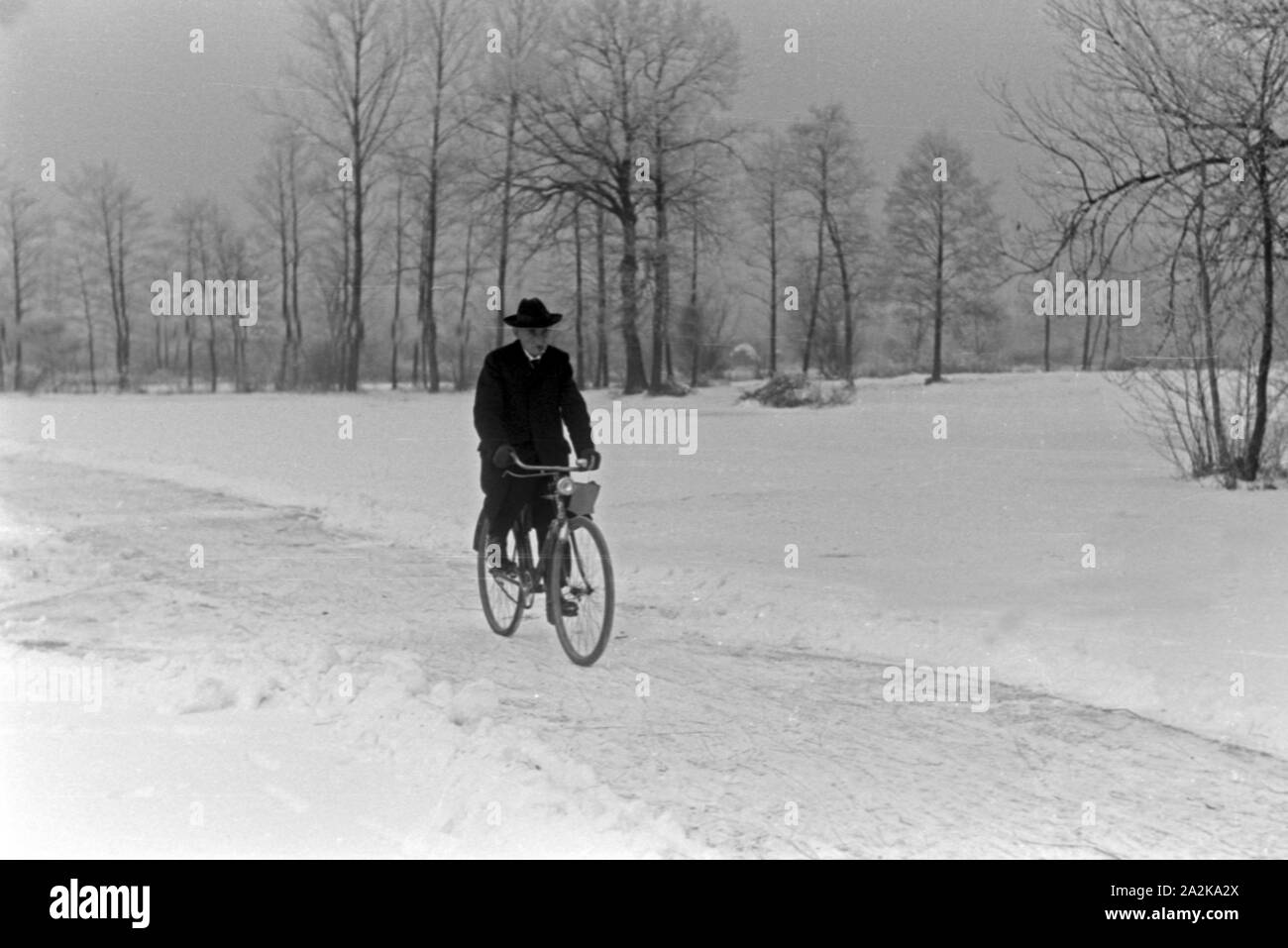 Ein Mann fährt mit dem Fahrrad durch den zugeschneiten Spreewald, Deutschland 1930 er Jahre. Un homme monté sur son vélo à travers la neige au domaine de Spreewald, Allemagne 1930. Banque D'Images