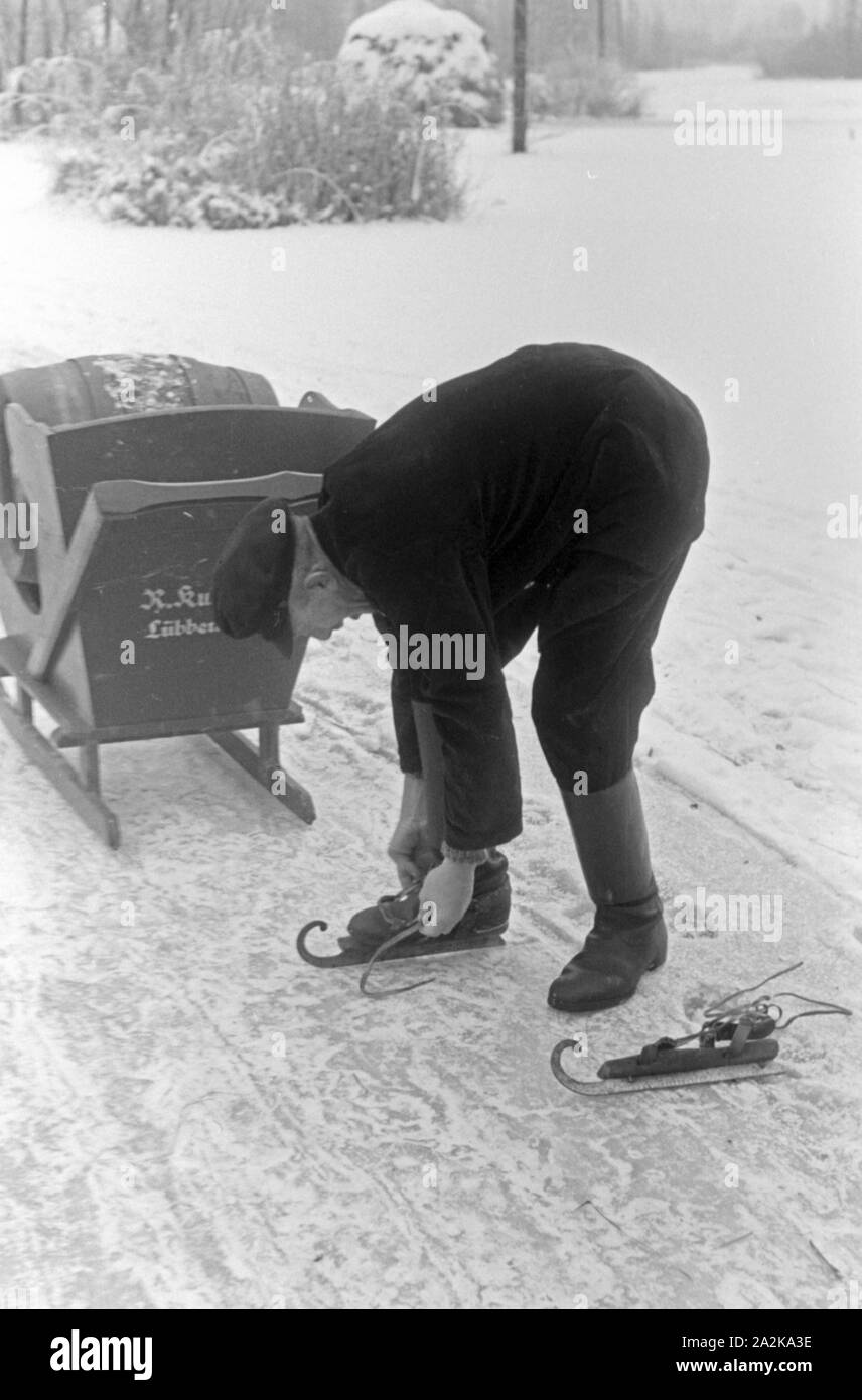 Schnallt Schlittschuhkufen sich ein Mann, une um mit dem Schlitten ein Fass Pils Schultheiss zu transportieren im Spreewald, Deutschland 1930 er Jahre. Mettre un homme sur son patin porteur à Spreewalad zone afin de transporter le baril de bière Schultheiss, Allemagne 1930. Banque D'Images