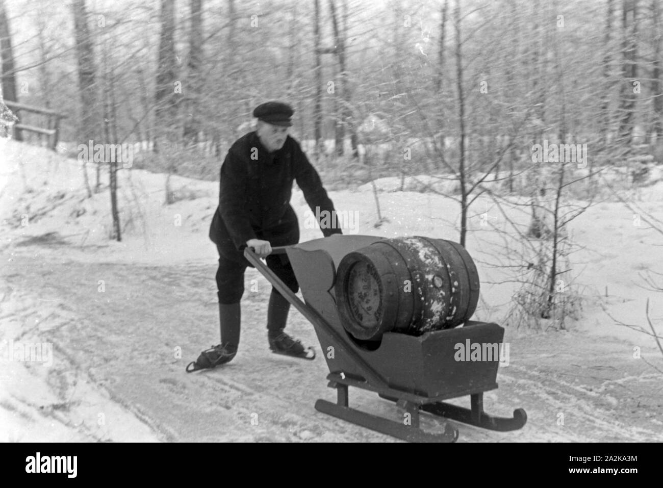 Ein Mann ein transportiert Fass Pilsener Schultheiss Schlitten auf einem durch den winterlichen Spreewald, Deutschland 1930 er Jahre. Un homme transportant un baril de bière Schultheiss sur un traîneau à travers une forêt d'hiver dans la région de Spreewald, Allemagne 1930. Banque D'Images