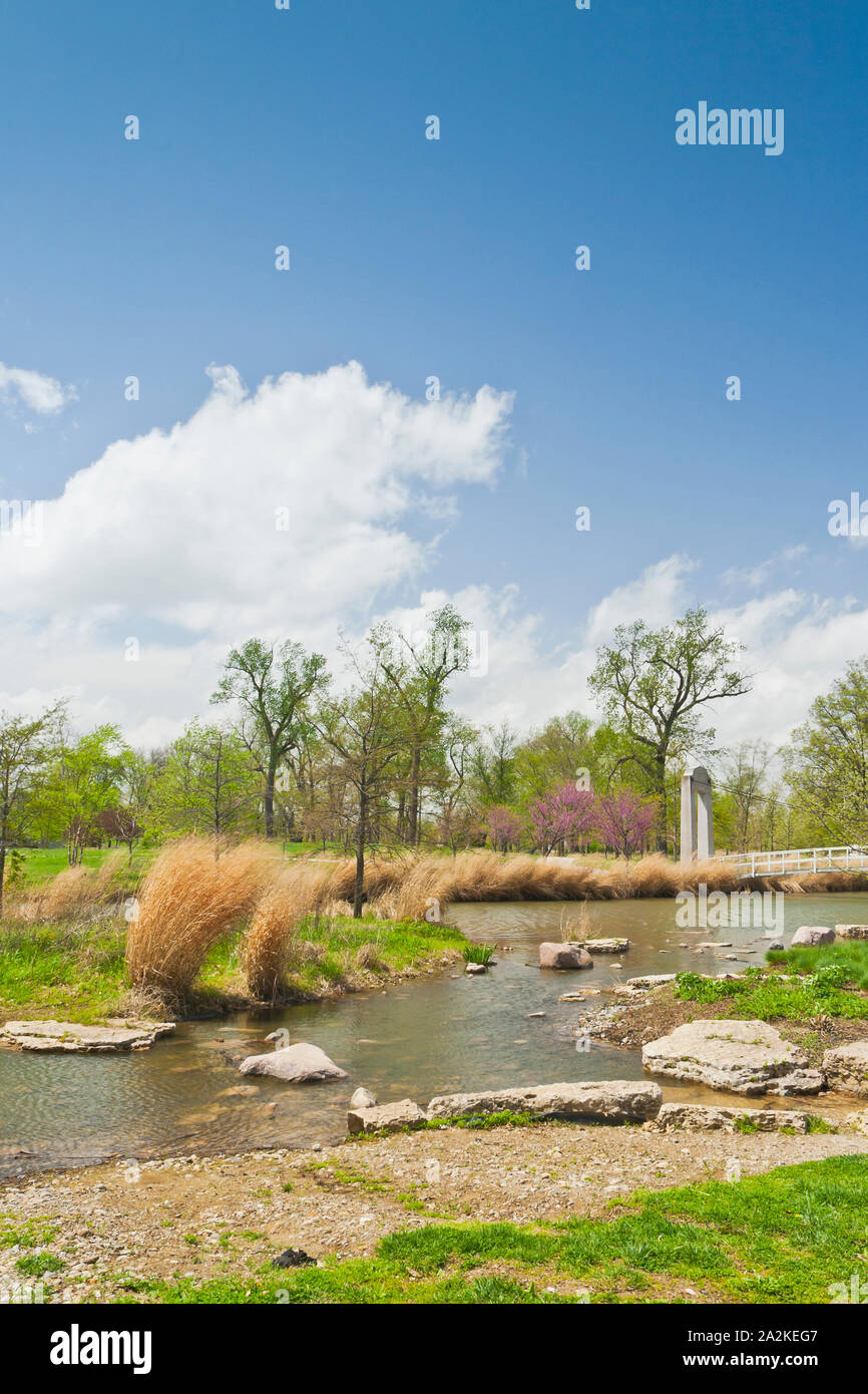 Puffy nuages flottent dans plus de redbud arbres avec des fleurs rose et le pont près du lac Post-Dispatch de rapides à St Louis Forest Park un jour de printemps. Banque D'Images