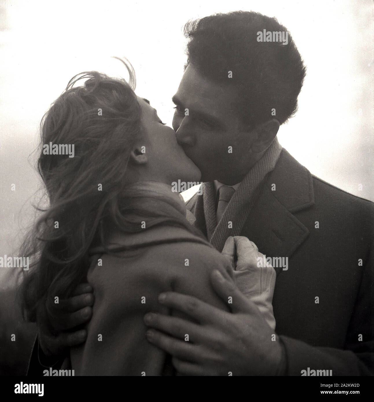 Années 1960, historique, un couple s'embrassant, un homme et une femme portant des manteaux à l'extérieur sur une colline ayant une romance, Angleterre, Royaume-Uni. Banque D'Images