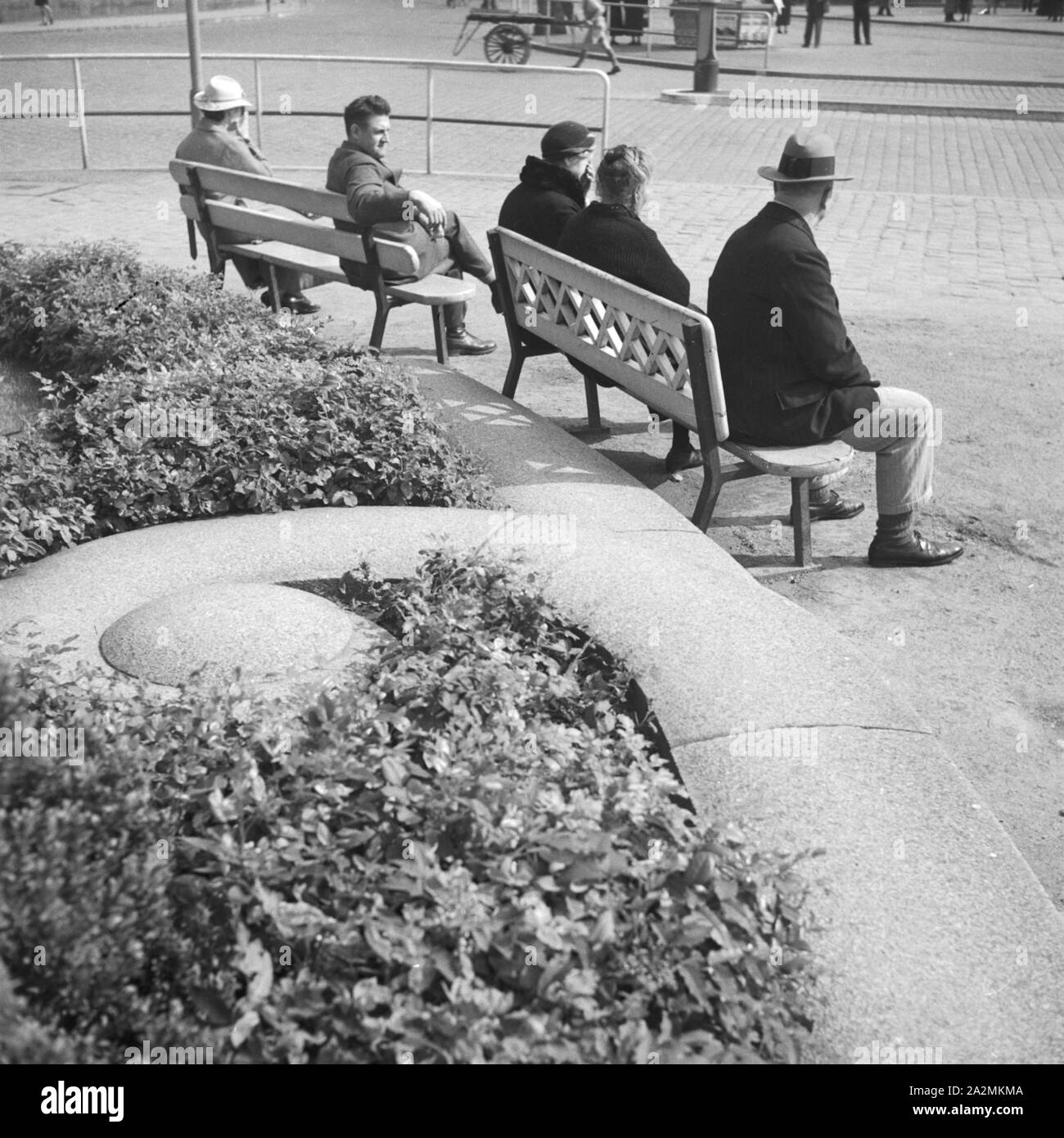 Passanten bei einer Pause auf einer Bank une einer Straße, Deutschland 1930er Jahre. Les passants en faisant une pause sur un banc par une rue, Allemagne 1930. Banque D'Images