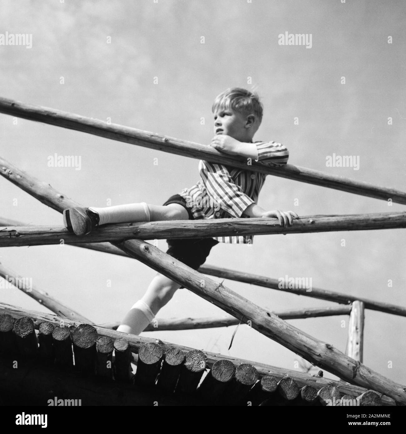 Ein Junge spielt und einem klettert un Holzgerüst, 1930er Jahre Deutschland. Un petit garçon jouer et grimper sur un cadre woodden, Allemagne 1930. Banque D'Images