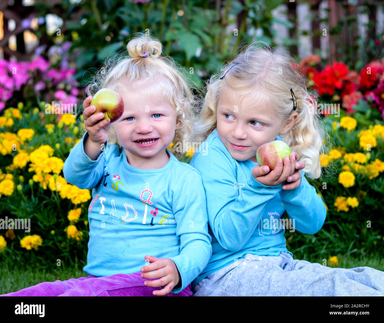 Deux blondes holding an apple Banque D'Images