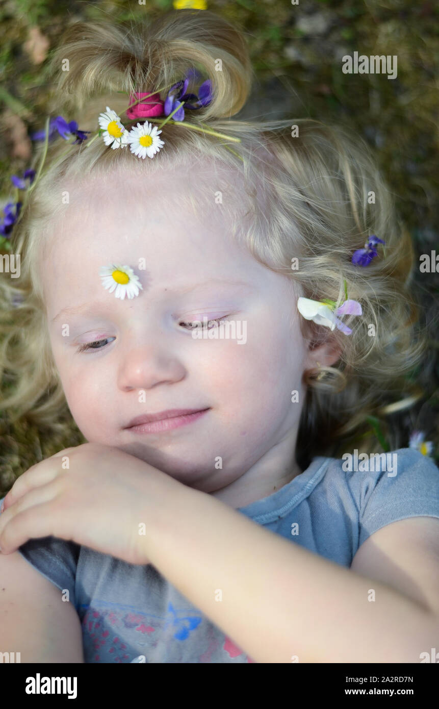 Girl couché dans l'herbe avec des fleurs dans les cheveux Banque D'Images