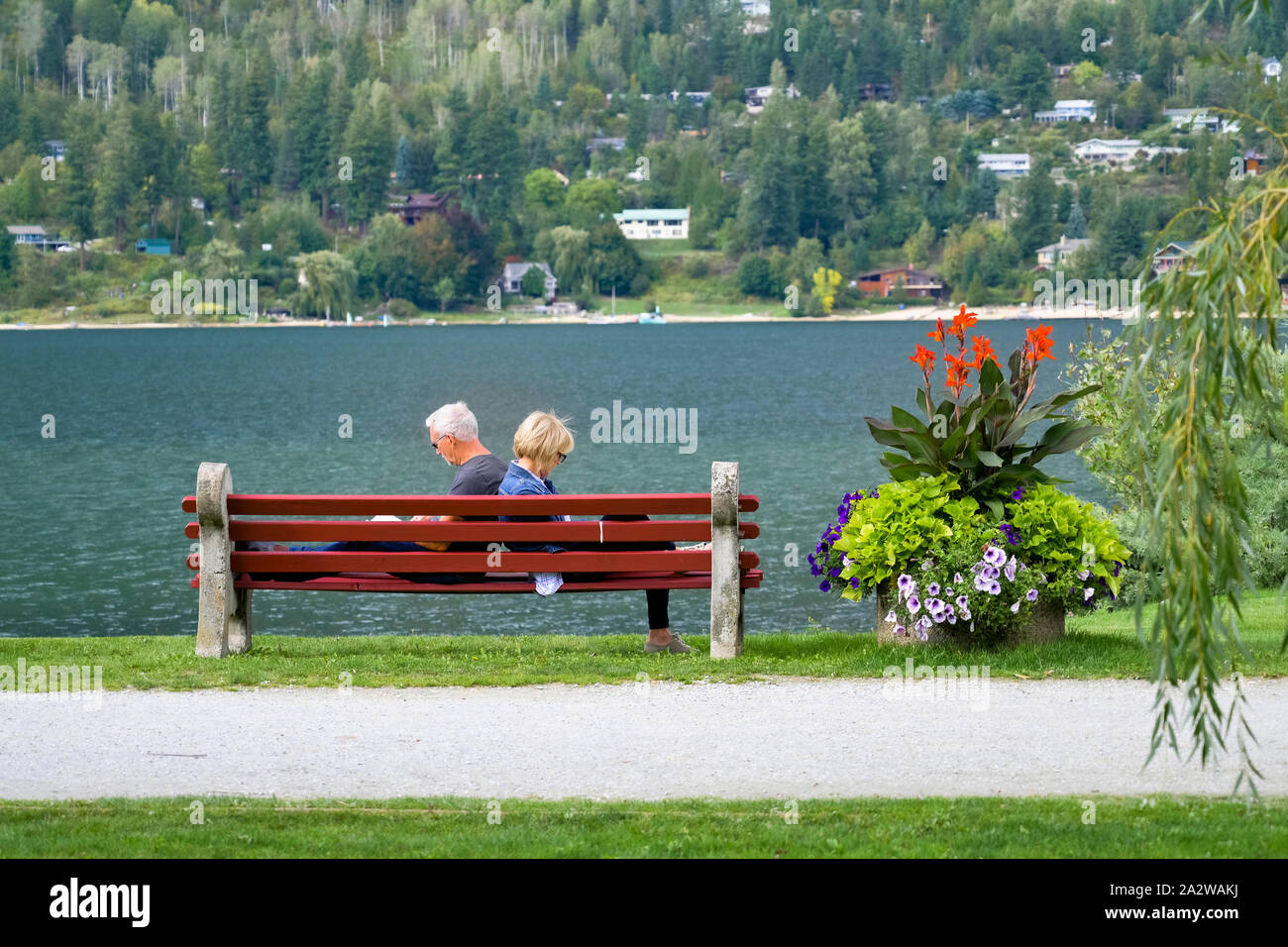 Couple reading on park bench, Lake Side Park, Nelson, Colombie-Britannique, Canada Banque D'Images