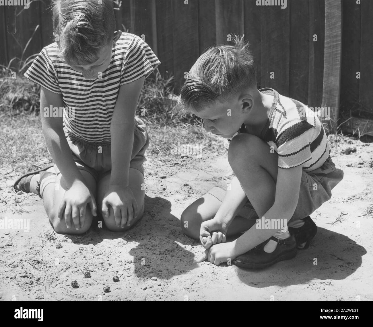 Photographie - garçons jouant aux billes, Dorothy Howard guidée, l'Australie, 1954, photographie noir et blanc représentant deux garçons jouant aux billes dans le sable, de l'Australie, 1954. Il fait partie d'un groupe de photographies prise par le folkloriste américain Dr Dorothy Howard alors qu'elle étudiait les jeux des enfants et playlore en Australie dans le cadre d'une bourse de recherche Fulbright,1954-1955. Ses photographies et la recherche sont devenues une partie de l'Australian Children's Folklore Collection à Banque D'Images