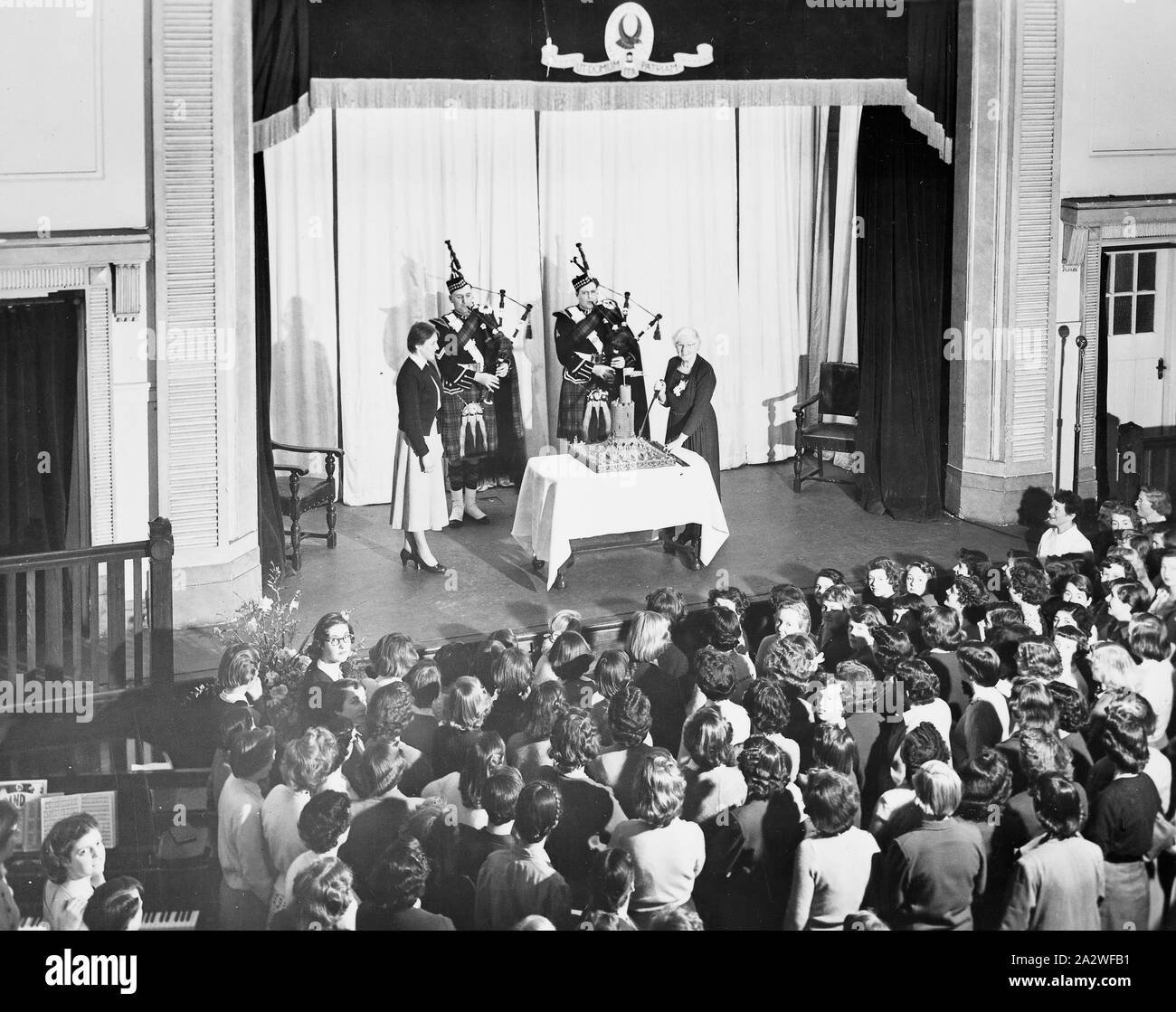 Négatif - Emily McPherson College Hall d'assemblage, Melbourne, Victoria, vers 1950, photographie négative de la salle de l'assemblée à Emily McPherson College. Sur la scène une femme est sur le point de couper un gâteau, vu par des étudiants ci-dessous. La photographie peut représenter l'ouverture de l'aile d'Ethel Margaret McPherson Emily McPherson College par Lady Hareng (un ancien médecin et d'un infatigable défenseur de l'éducation et de bienfaisance facilites) le 16 août 1950 ou la fondation de l'aile Banque D'Images