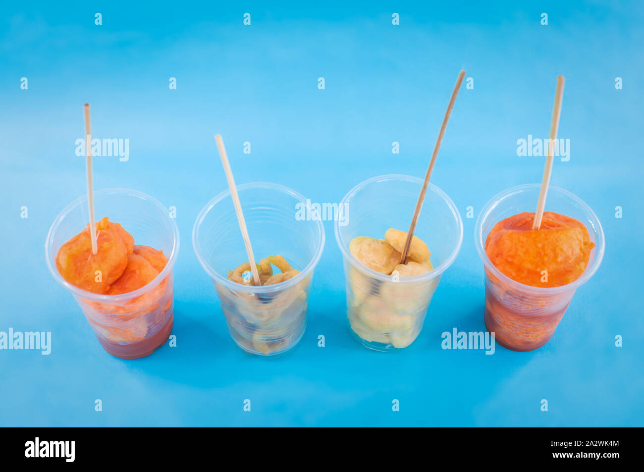 Une divers aliments de rue philippins sur une tasse en plastique avec des bâtons sur fond isolé bleu. Philippines L'alimentation de rue et leurs noms comme Kwek - Kwek Banque D'Images