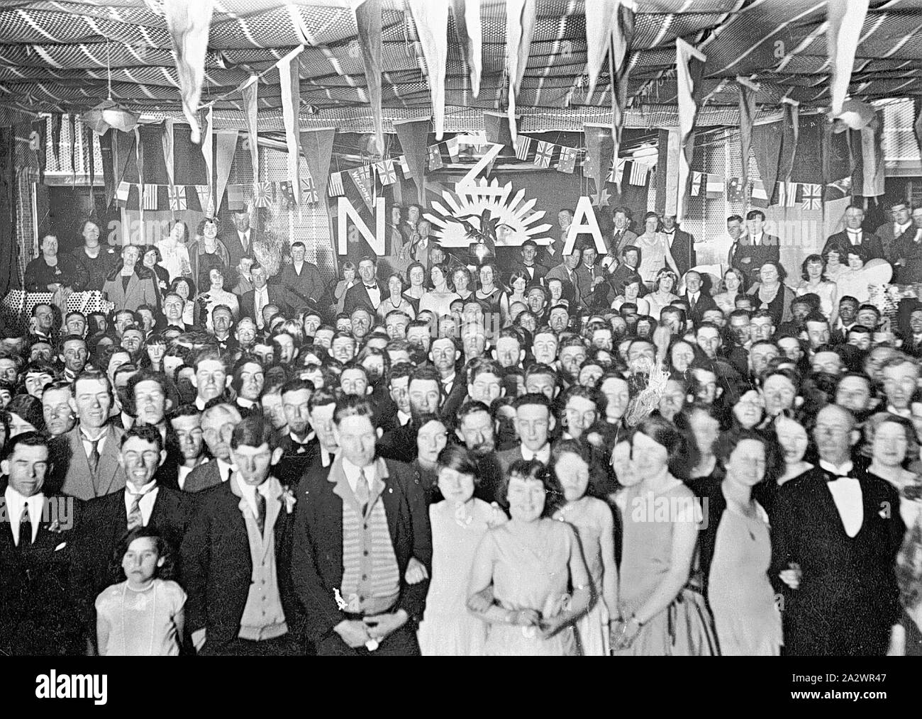 Négatif - Manangatang, Victoria, 1931, un rassemblement de personnes, à un R.S.L. ball. Des lettres sur une bannière à l'arrière-plan lire "NZA' sur un soleil levant Banque D'Images