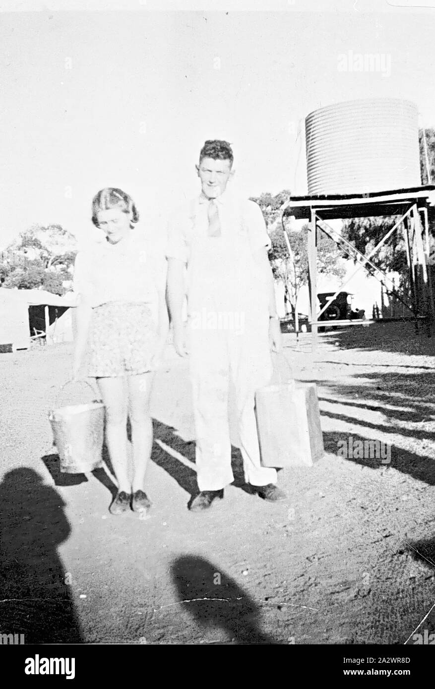 Négatif - Annie et Ryan Lewis Gibson transportant des seaux, Chinkapook, Victoria, 1935, un homme (Lewis Gibson) et une fille (Annie Ryan) transportant des seaux de lait après la traite Banque D'Images