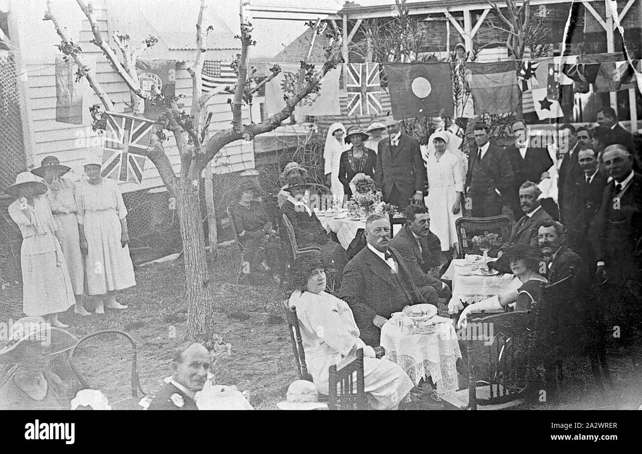 Négatif - l'Association des autochtones australiens, célébration de la Première Guerre mondiale, Charleville, Queensland, 1923, une célébration organisée par l'Association des autochtones australiens. Un certain nombre de personnes s'asseoir au petit plateau tables dans une arrière-cour, tandis que d'autres se regarder. Il y a des drapeaux suspendus sur une ligne et d'une arborescence. Certaines des femmes portent des uniformes d'infirmières. L'Association des autochtones de l'Australie était une société qui offrait des avantages à ses membres nés en Australie. Il a été un ardent défenseur de la protection du commerce Banque D'Images