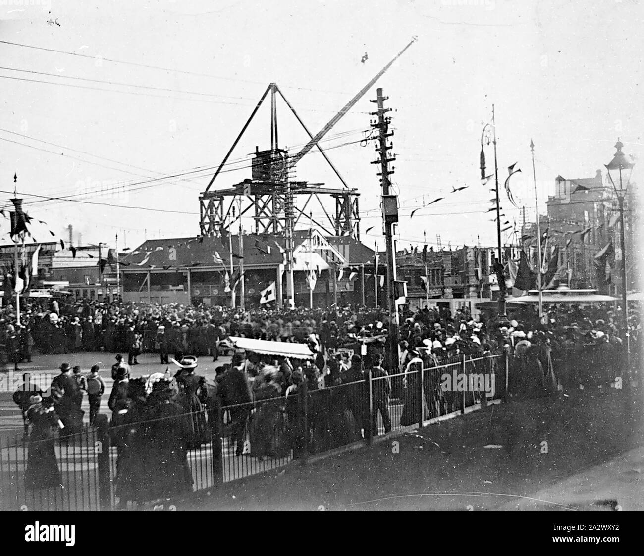 Négatif - Melbourne, Victoria, 1913, la construction de la gare de Flinders Street. Il y a une grande grue sur une plate-forme en arrière-plan. Il y a de grandes foules de Swanston Street et banderoles sur les poteaux Banque D'Images