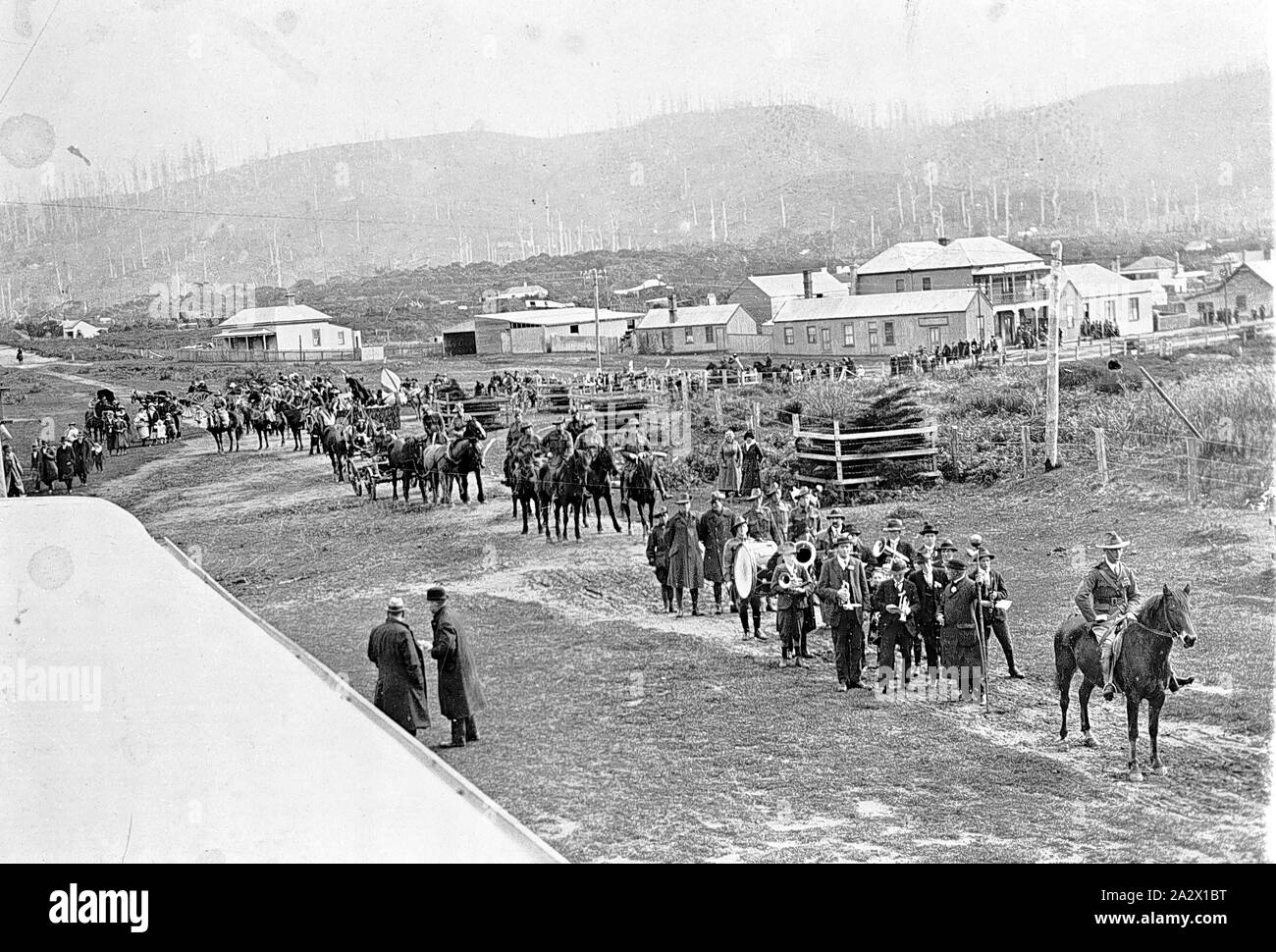Négatif - La Journée de la Procession, Victoria, vers 1920, une procession de la journée de la paix à travers un pays ville. Un homme à cheval mène la procession, suivi d'une fanfare Banque D'Images