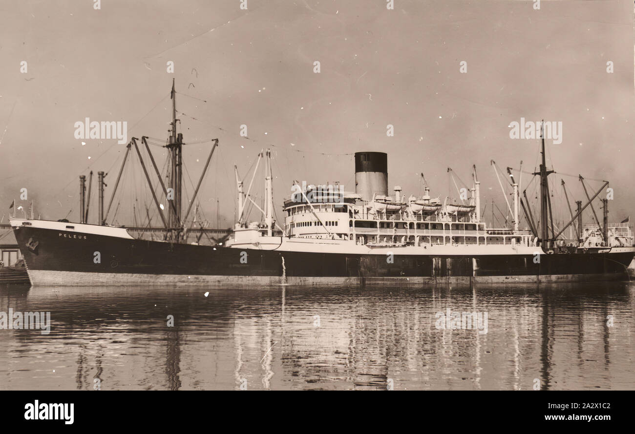 Négatif - SS Pélée amarré au port inconnu, vers 1949, vue sur la ligne d'expédition de l'entonnoir de Pélée SS navire accosté à un port inconnu. L'un des six copies de négatifs photographiques en noir et blanc représentant des navires et des outils de navigation maritime qui se rapportent à M. Martin l'Spencer-Hogbin carrière de navigant. Né en Angleterre en 1924 Spencer-Hogbin Martin a passé sa vie à travailler dans l'industrie maritime travaillant principalement pour le Blue Funnel Line. En 1957, Martin a décidé de Banque D'Images