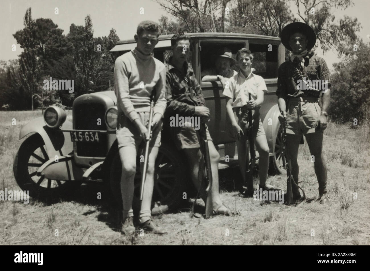 Photographie - Boxing Day Groupe de chasse avec Chevrolet Motor Car, Bourton on the water, Victoria, 1949, portrait de groupe de quatre hommes et un garçon avec des fusils. Une Chevrolet voiture est garée à côté du groupe, la brousse, est illustré dans l'arrière-plan Banque D'Images