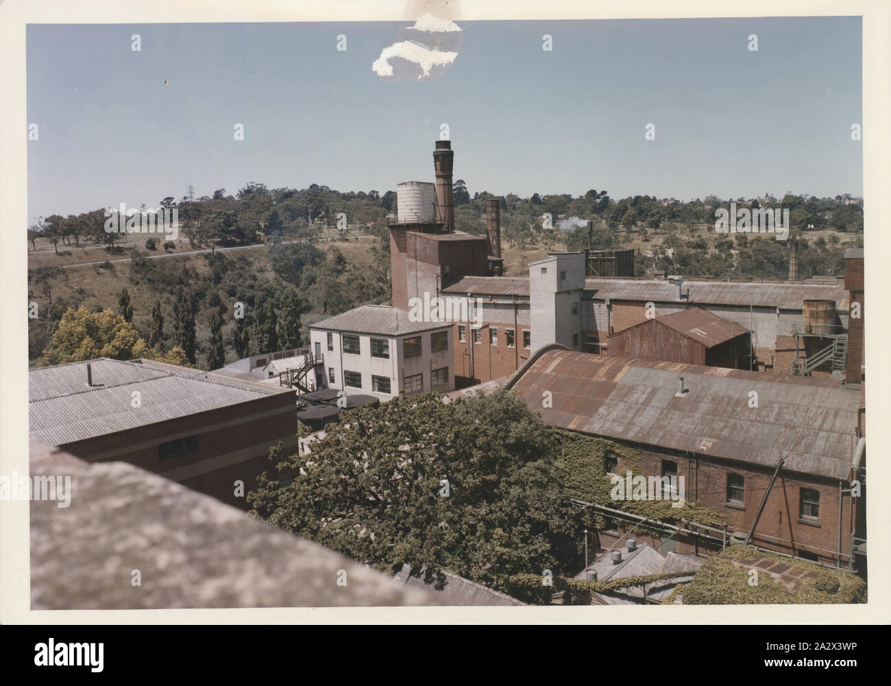 Photographie, Kodak anciens bâtiments d'usine montrant réservoir d'eau et cheminée, Abbotsford, Victoria, vers 1980, photographie couleur de Kodak Australasia Pty Ltd d'anciens bâtiments d'usine à Abbotsford, vers 1980. Les toits métalliques de divers bâtiments sont indiqués, y compris une cheminée avec réservoir d'eau sur le dessus. Le mot 'Kodak' peut encore être vu sur l'une des cheminées. partie d'une collection de documents de recherche et d'artefacts assemblés par d'anciens employés de Kodak Australasia Nigel Beale tandis qu'il était Banque D'Images