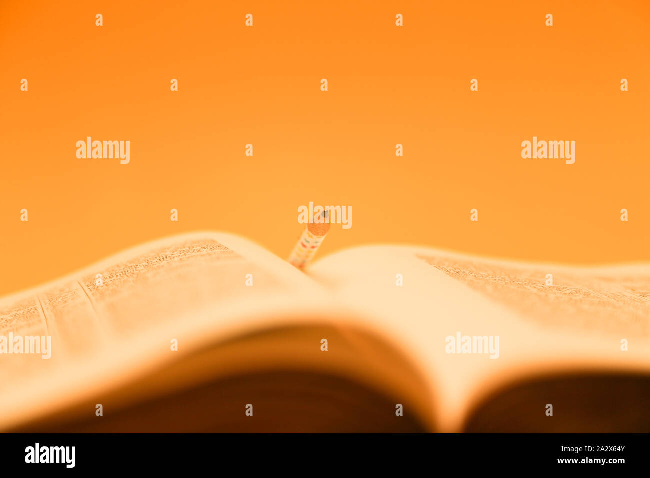 Bible avec un crayon dans les pages. Récolte de couleur or de bible, sur jaune Banque D'Images