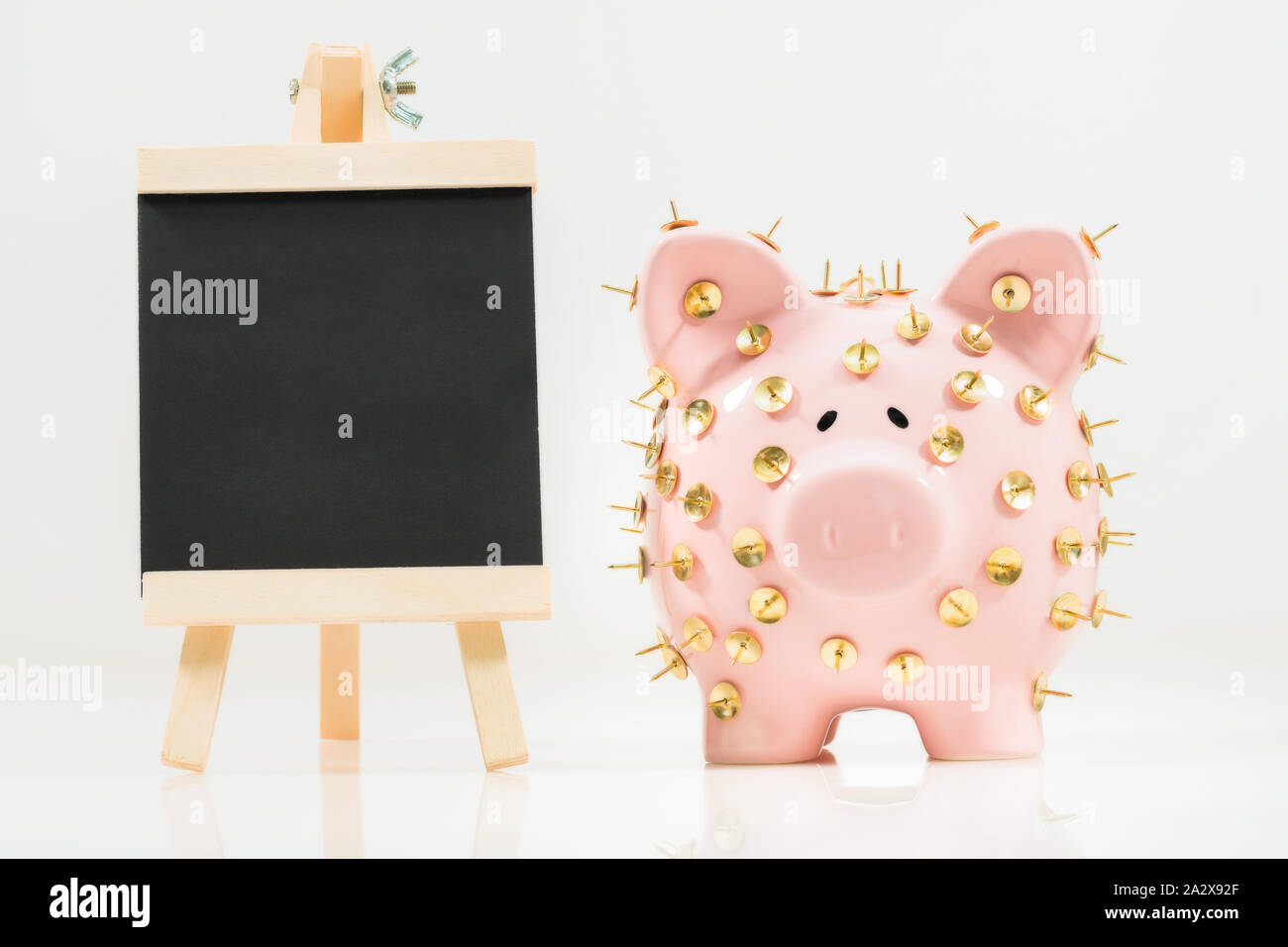 Image conceptuelle illustrant la protection des économies et des investissements montrant une banque de porc rose protégée par des piles de dessin et isolée contre le blanc. Banque D'Images